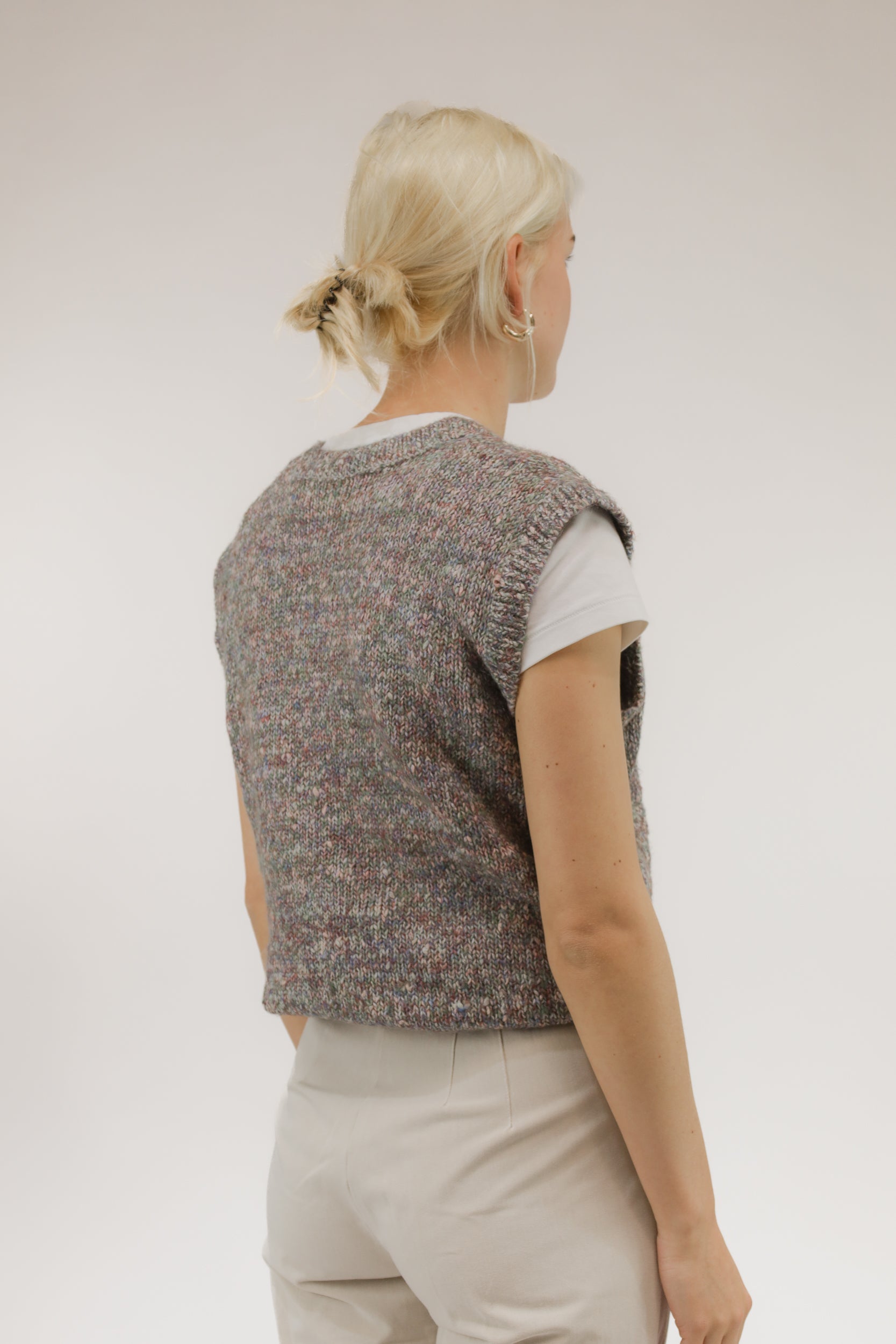 Model van achteren met vintage spencer in rood en paars melange – zachte breistructuur zichtbaar.