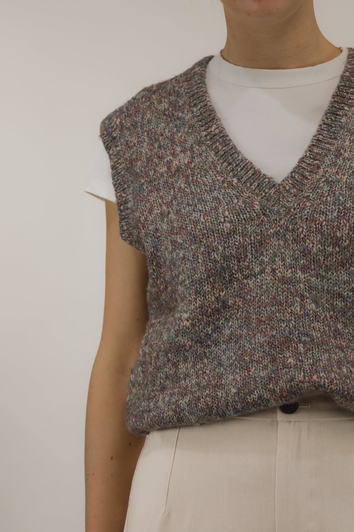 Close-up van model met vintage spencer – detail van melange garen en warme kleurtinten.