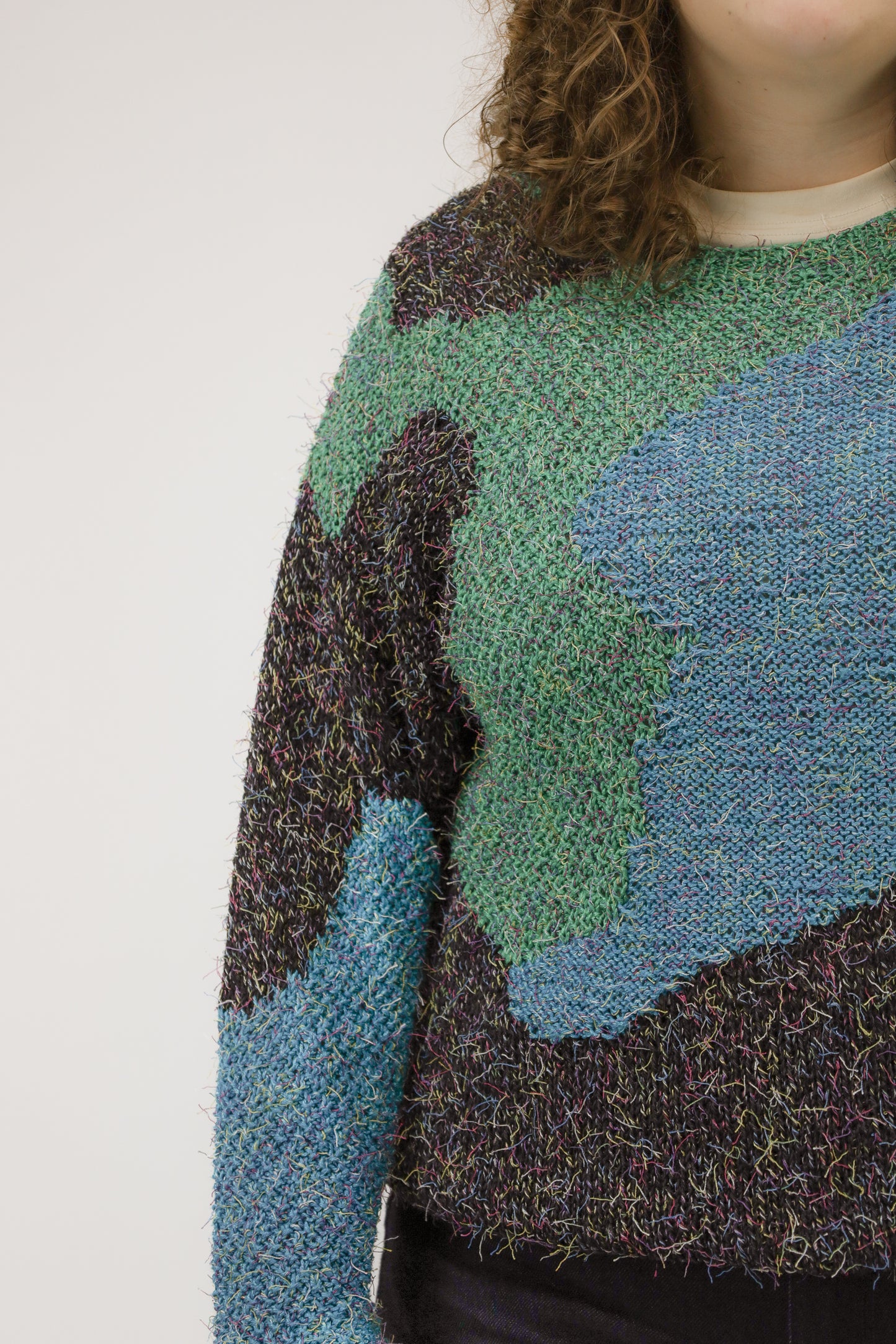 Close-up van model met vintage trui – detail van gemêleerd garen met losse draadjes en organische vormen.