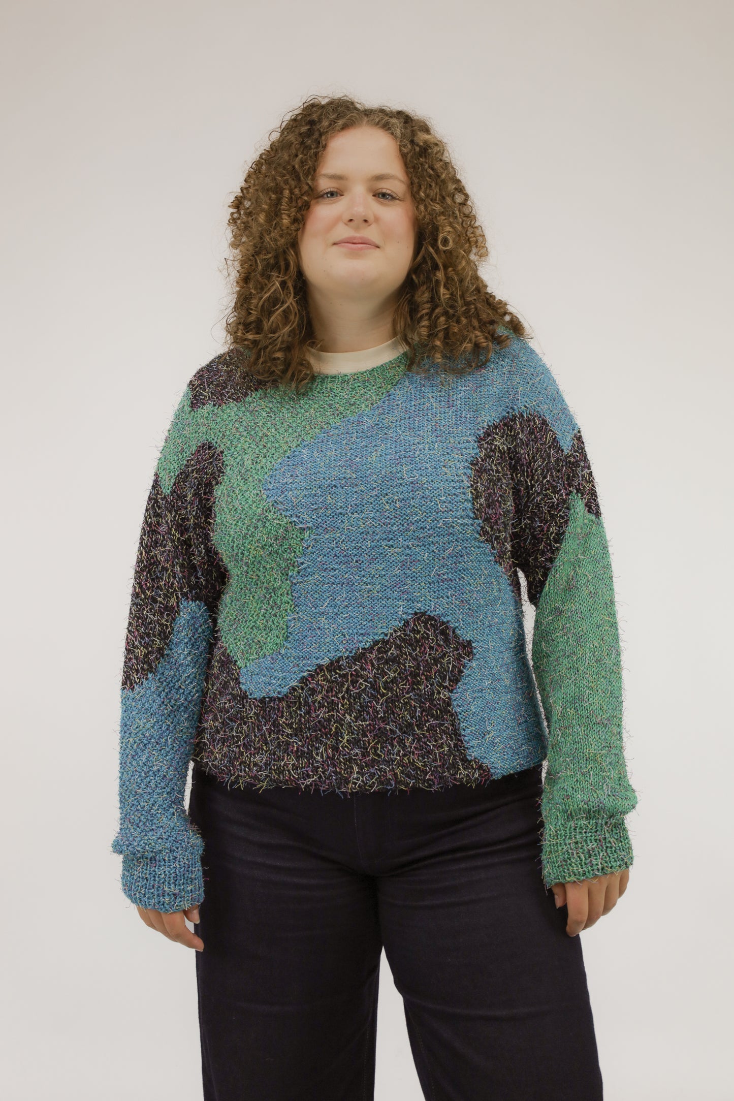 Model draagt vintage oversized trui met organisch dessin in zwart, groen en blauw – vooraanzicht.