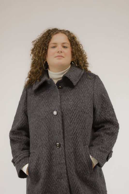 Vooraanzicht van model met blauwgrijze vintage alpaca jas met knoopsluiting.