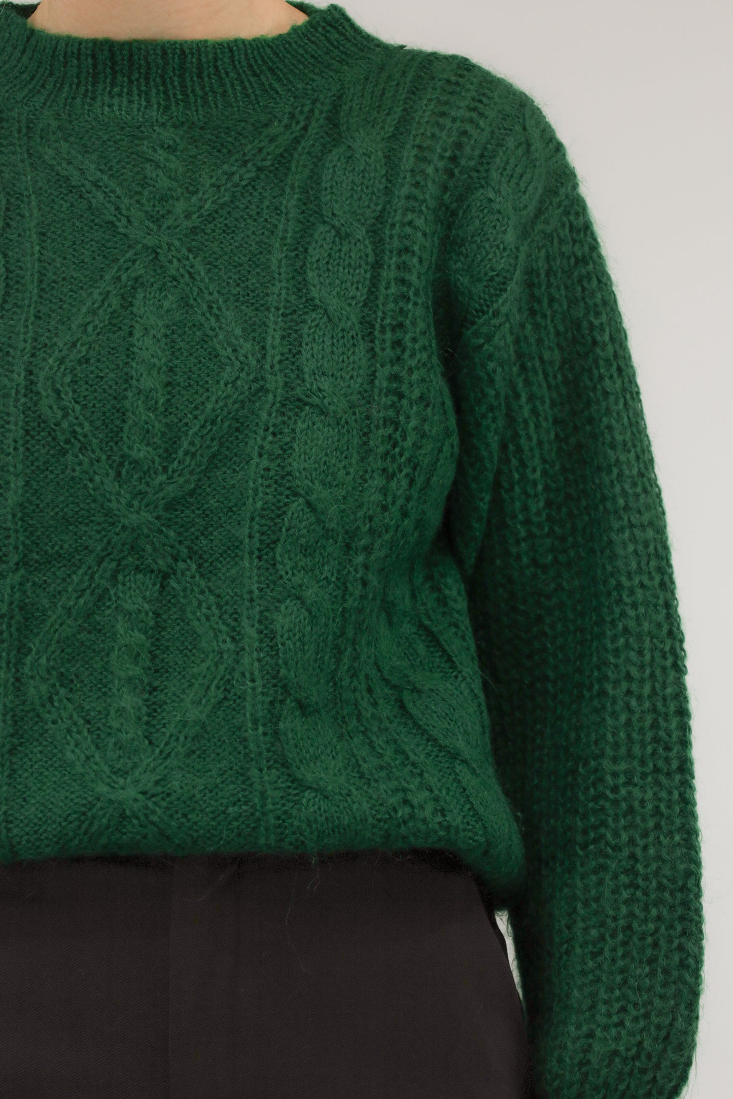 Close-up van model met vintage trui – detail van mohairstructuur en ingeweven kabelpatroon in rijke groene tint.