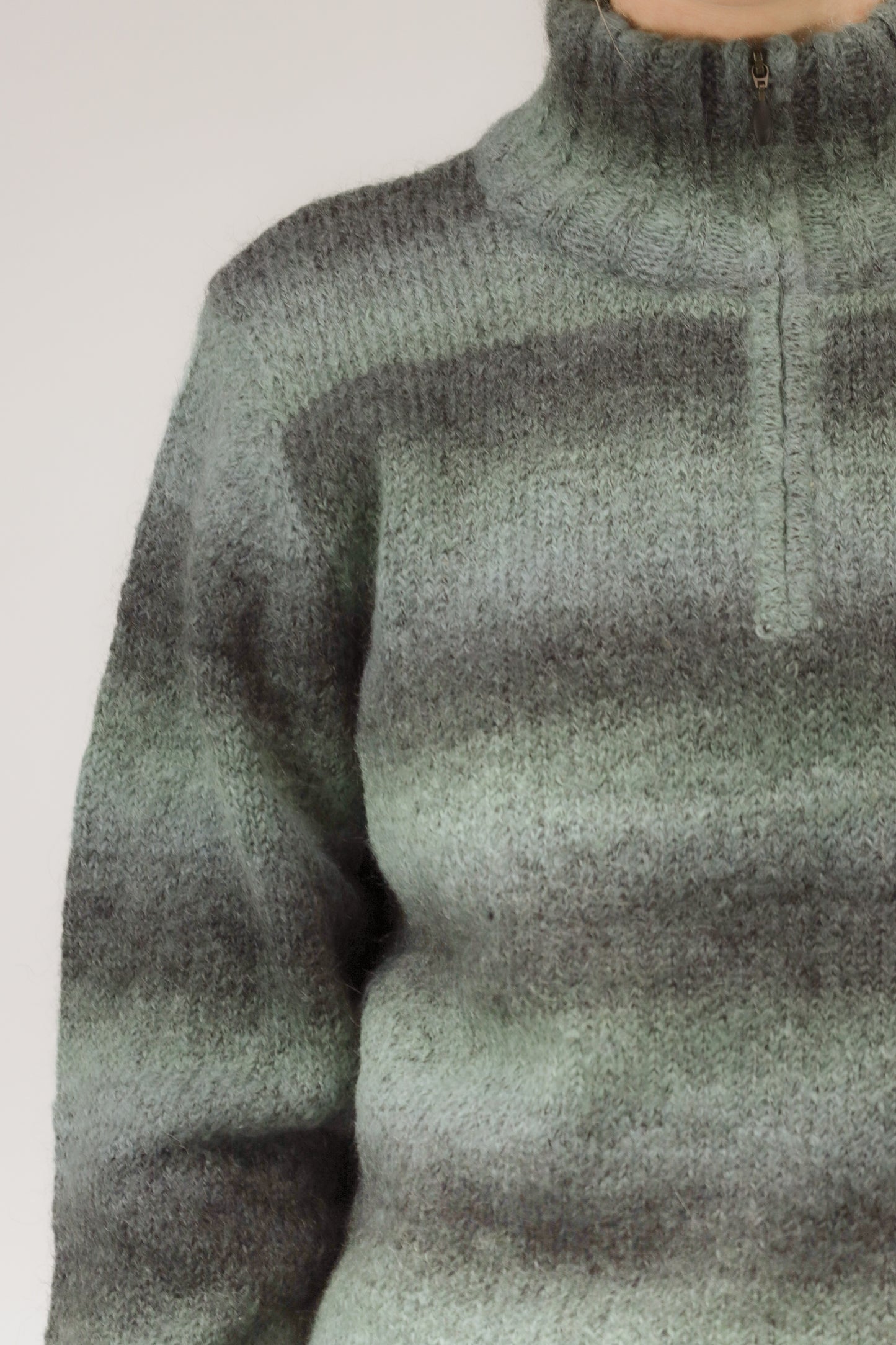 Detailopname van mohairstructuur, rits en gestreept patroon van de trui.