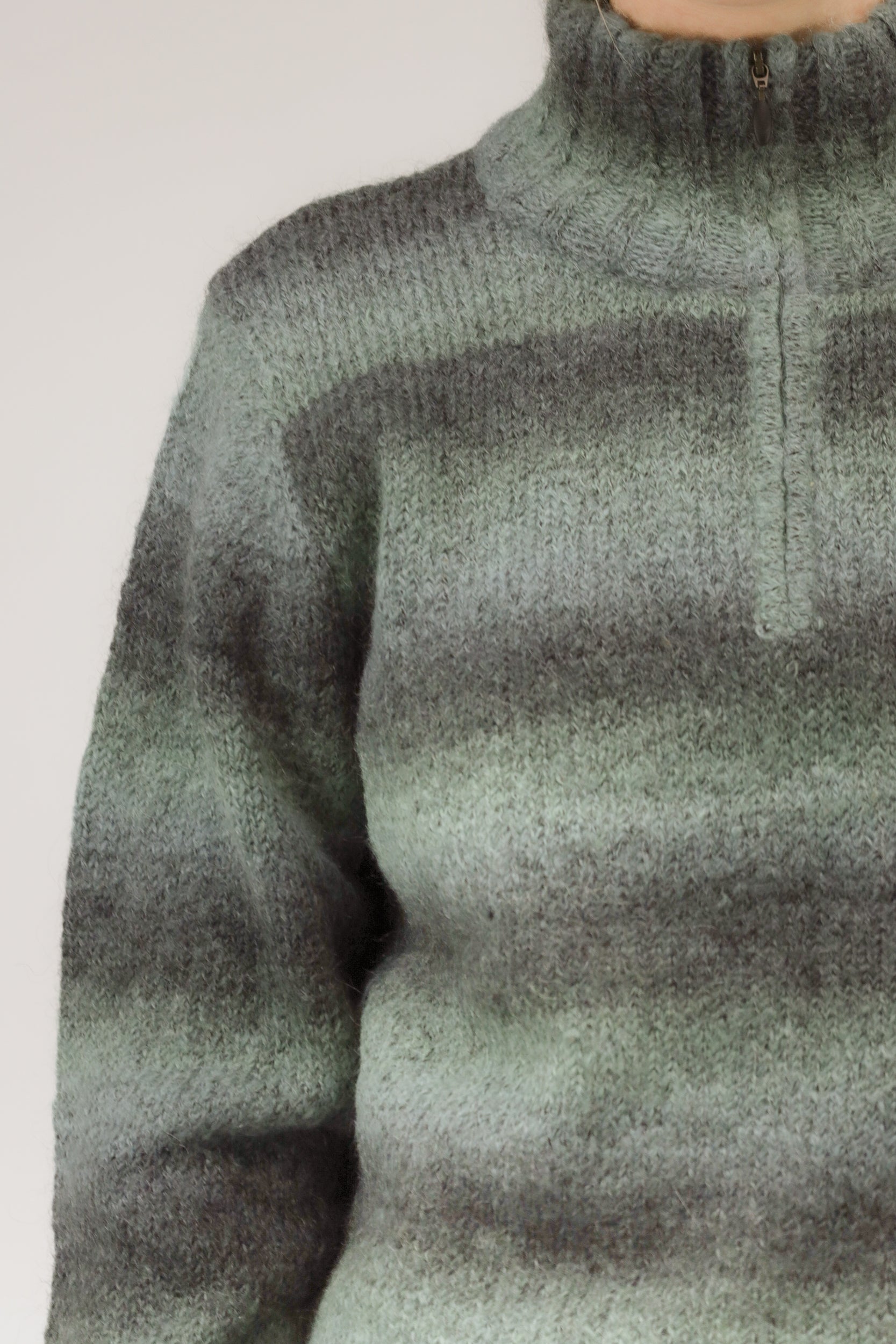 Detailopname van mohairstructuur, rits en gestreept patroon van de trui.