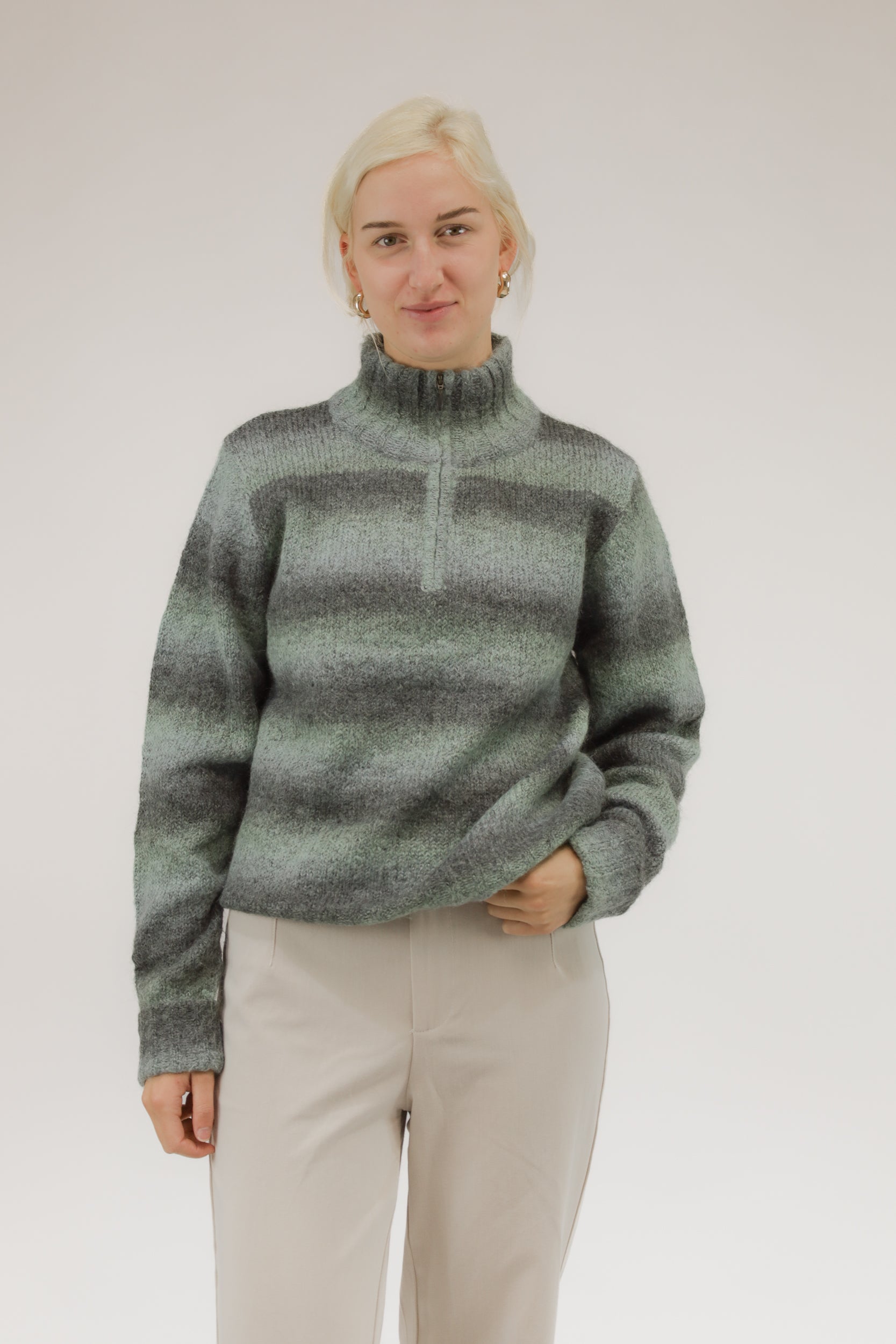 Vooraanzicht van model met groen-grijs gestreepte vintage trui met col en rits middenvoor.