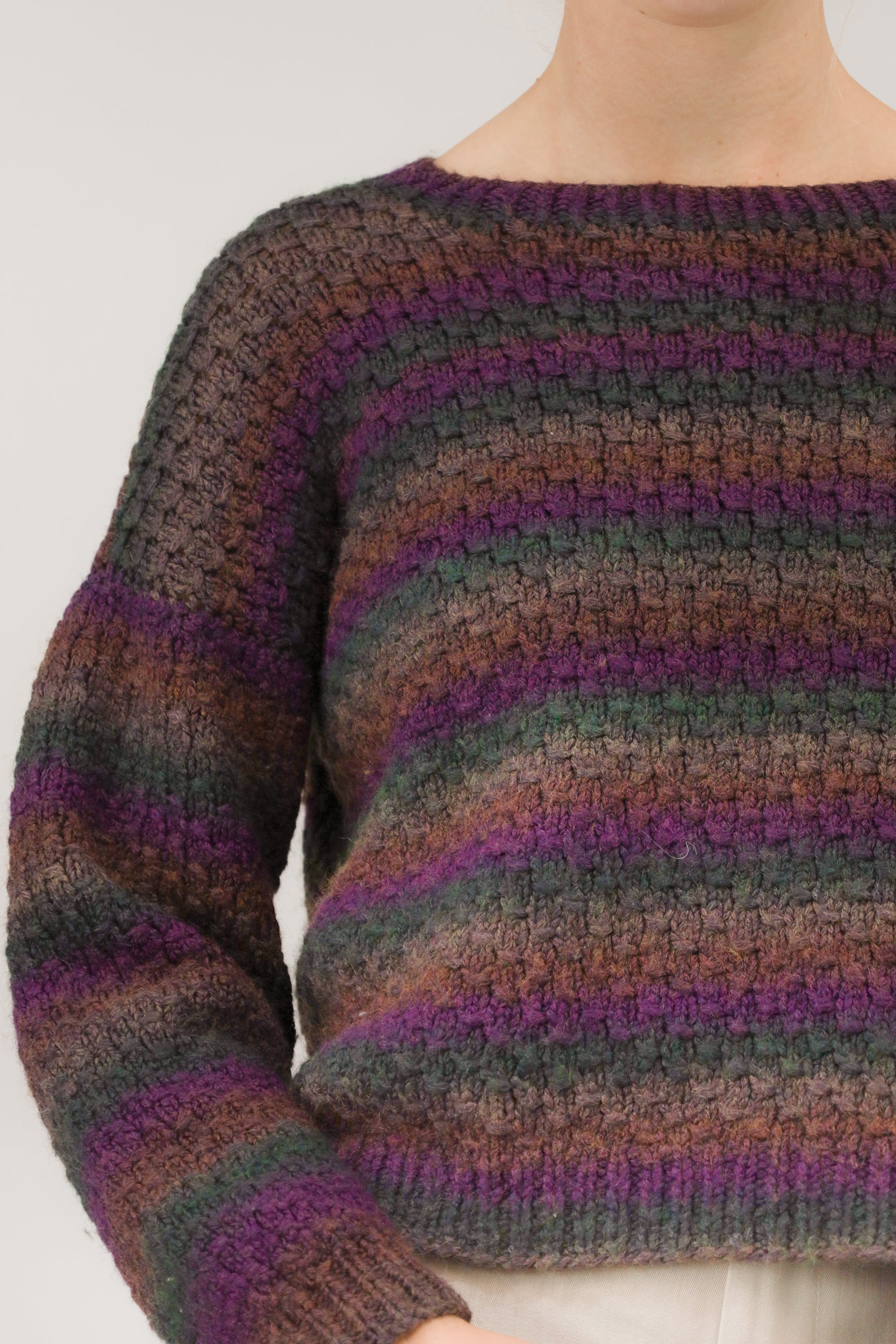 Close-up van model met vintage trui – detail van grof breisel en kleurencombinatie in strepen.