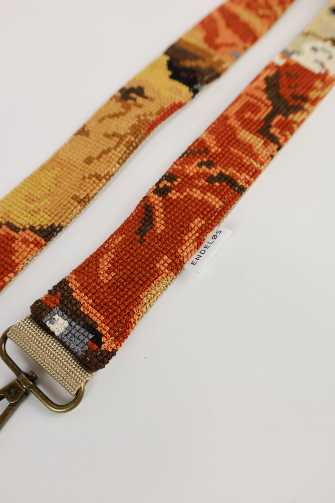 Close-up van de strap met borduurwerk van The Red Boy, adding a bold and unique flair to your accessories.