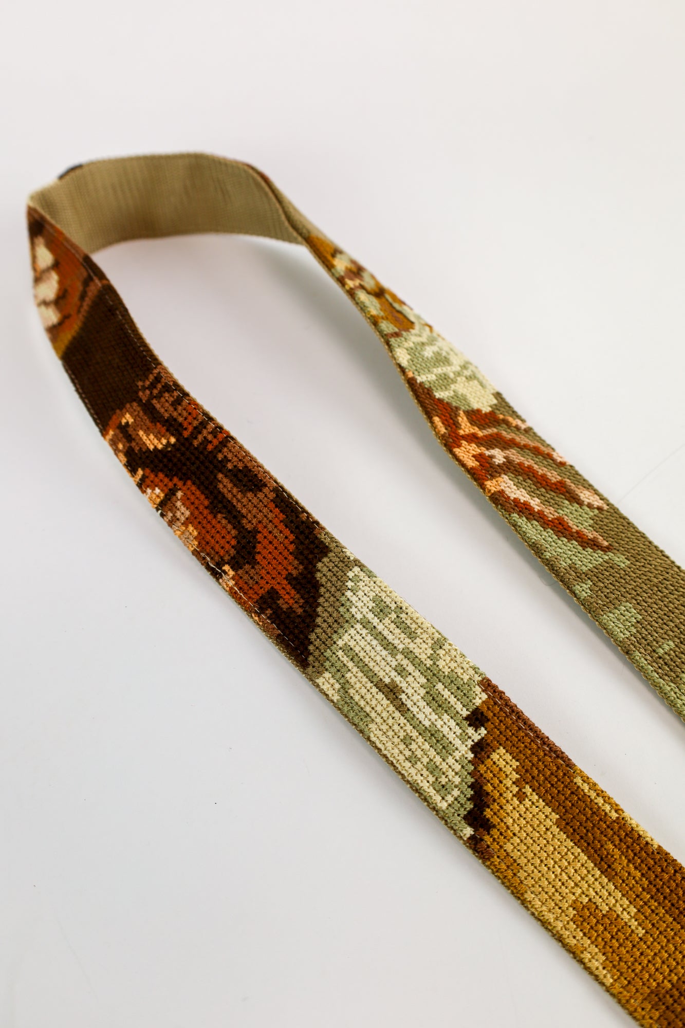 Close-up van de strap met geborduurd schilderij van De Vrolijke Drinker, perfect voor tas, telefoon of camera.