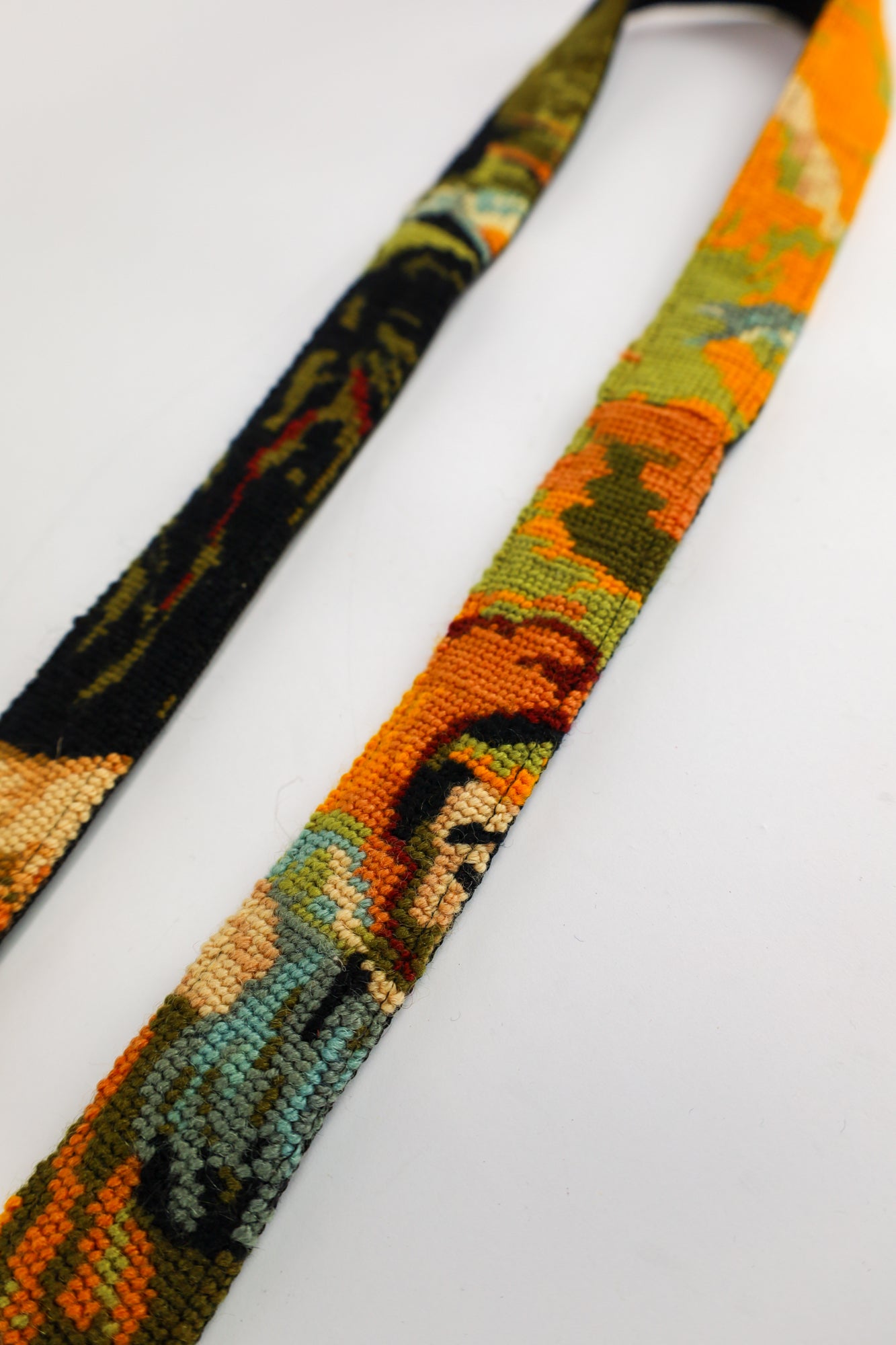 Handgemaakte strap featuring an embroidered vintage painting with vibrant orange hues, adding style and personality.