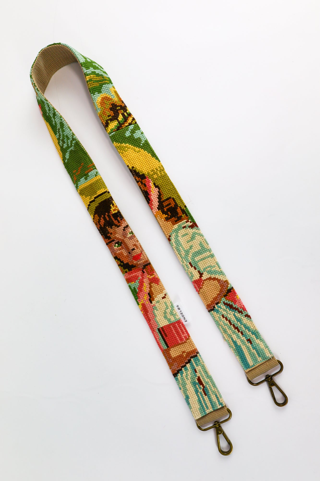 Strap made from re-used materials with colorful embroidered painting of a girl with a hat, a unique addition to your bag, phone, or camera.