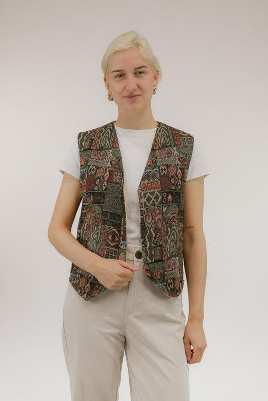 Model draagt vintage jacquard geweven gilet in groen en roodtinten – vooraanzicht, open model zonder sluiting.