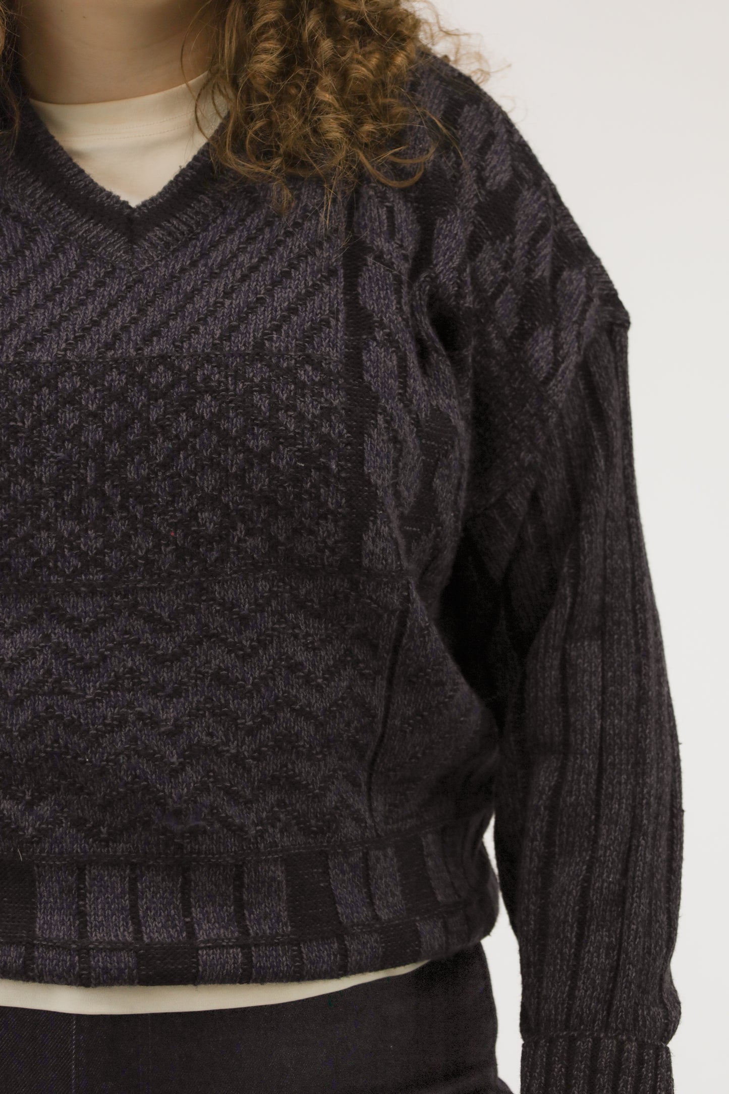 Close-up van model met vintage trui – detail van grafisch breisel met paarse en donkerblauwe accenten.