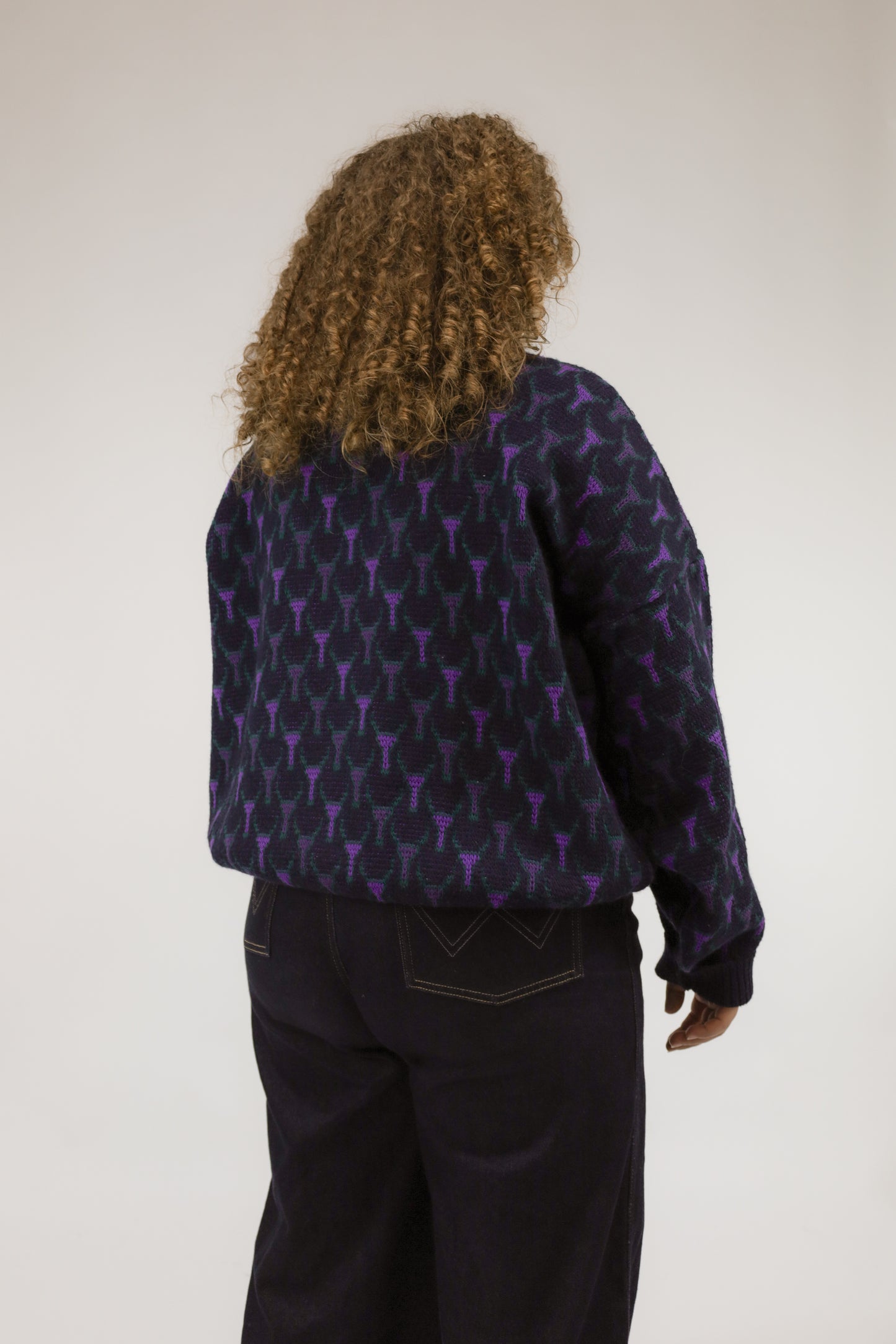 Model van achteren met donkerblauwe vintage trui – all-over dessin en zachte wol-acryl textuur.