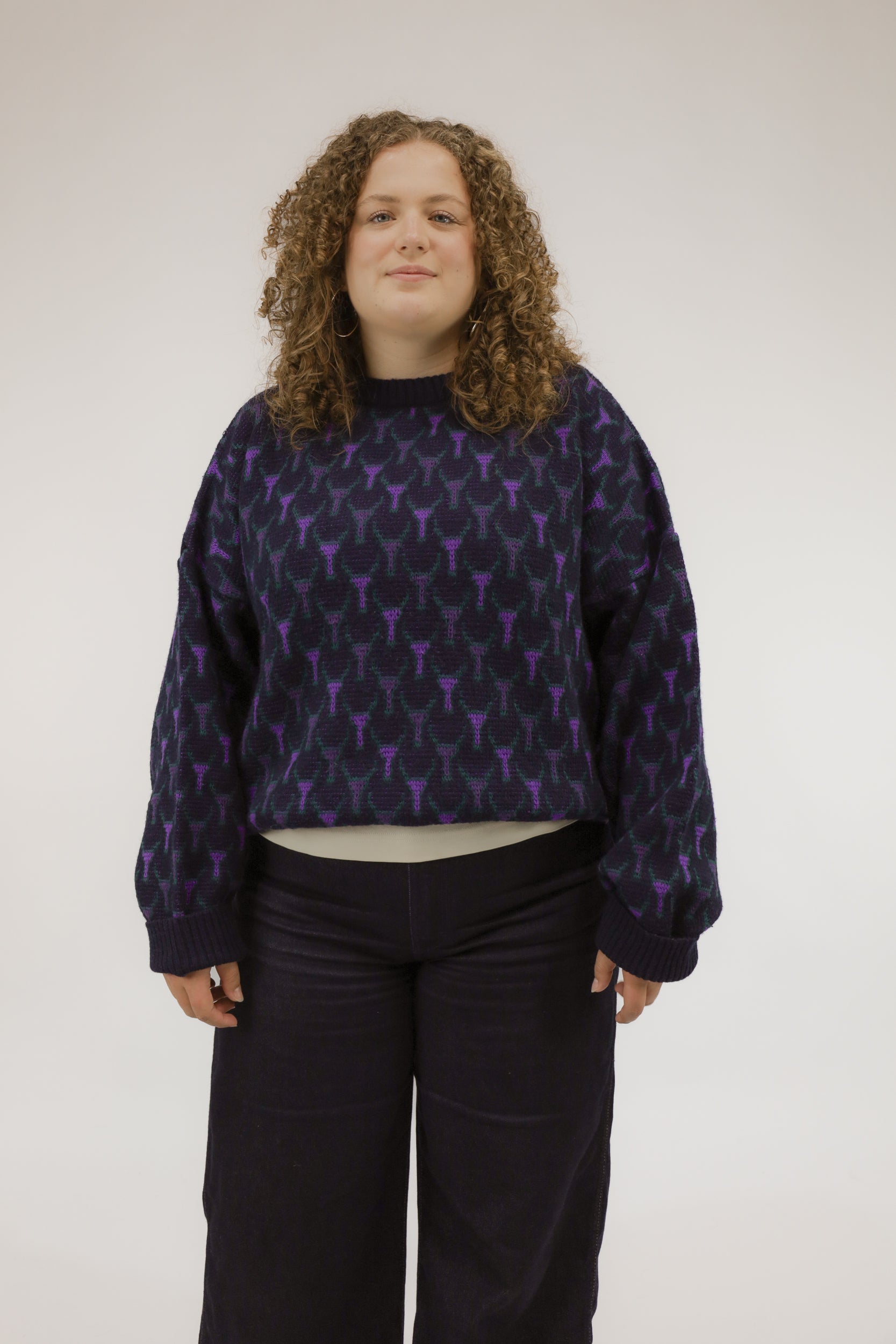 Model draagt donkerblauwe vintage trui met grafisch ingebreid dessin in paars en groen – vooraanzicht.