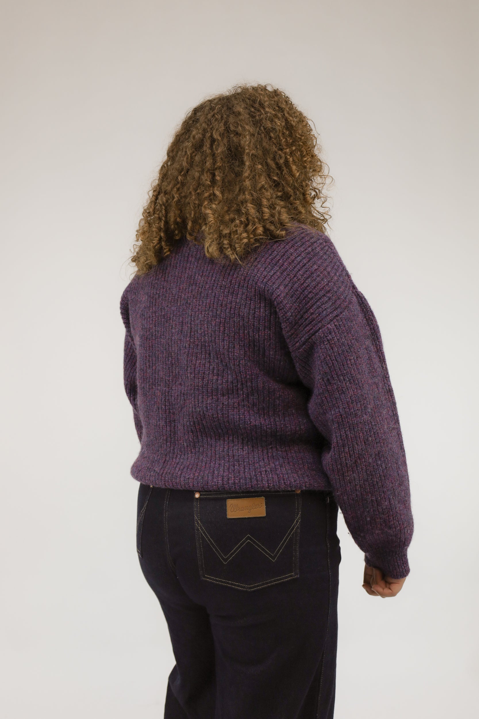 Model van achteren met paars gemêleerde vintage trui – zachte wollen textuur en losse pasvorm.