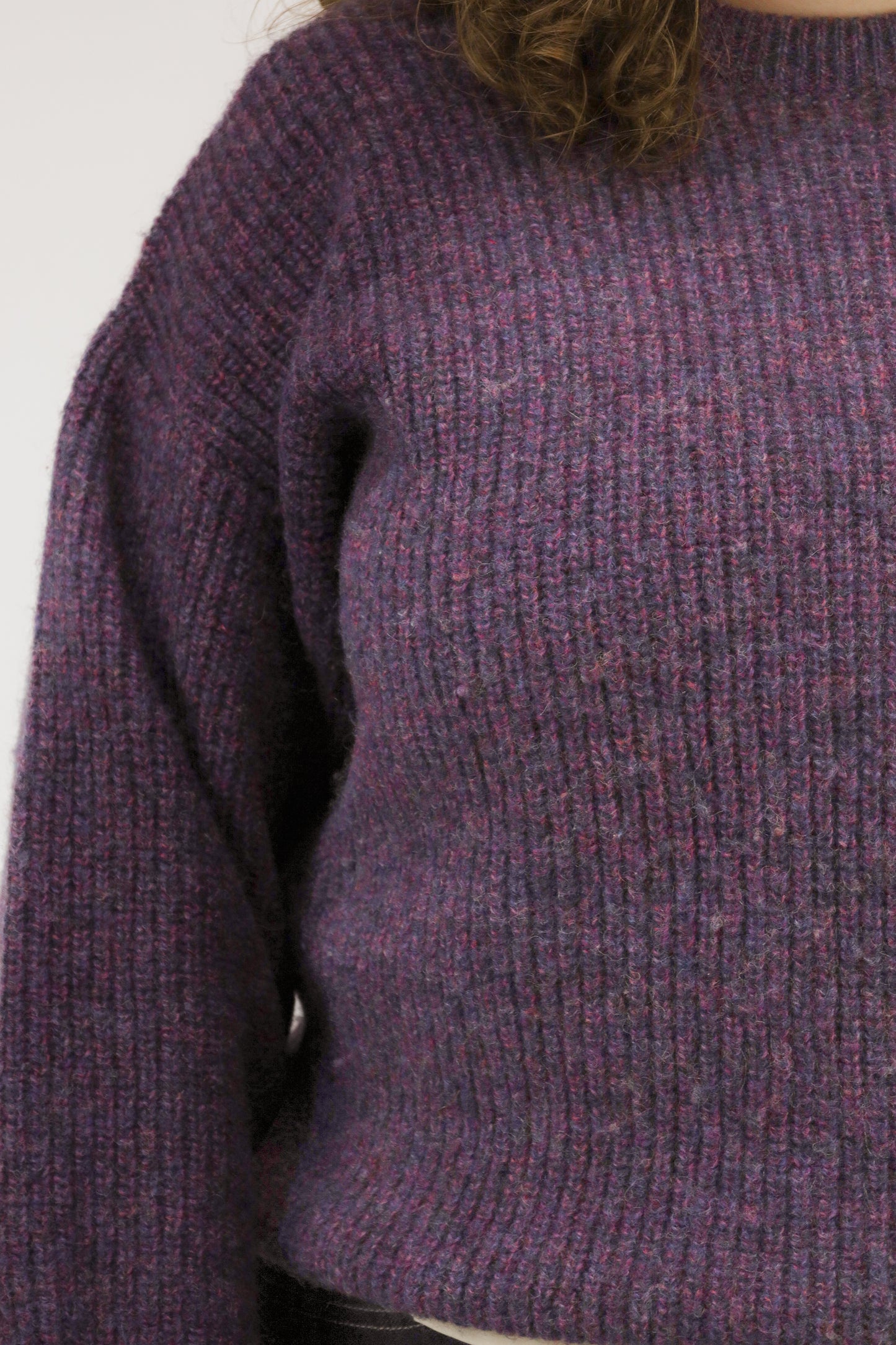 Close-up van model met vintage wollen trui – detail van gemêleerde paarse wolstructuur.