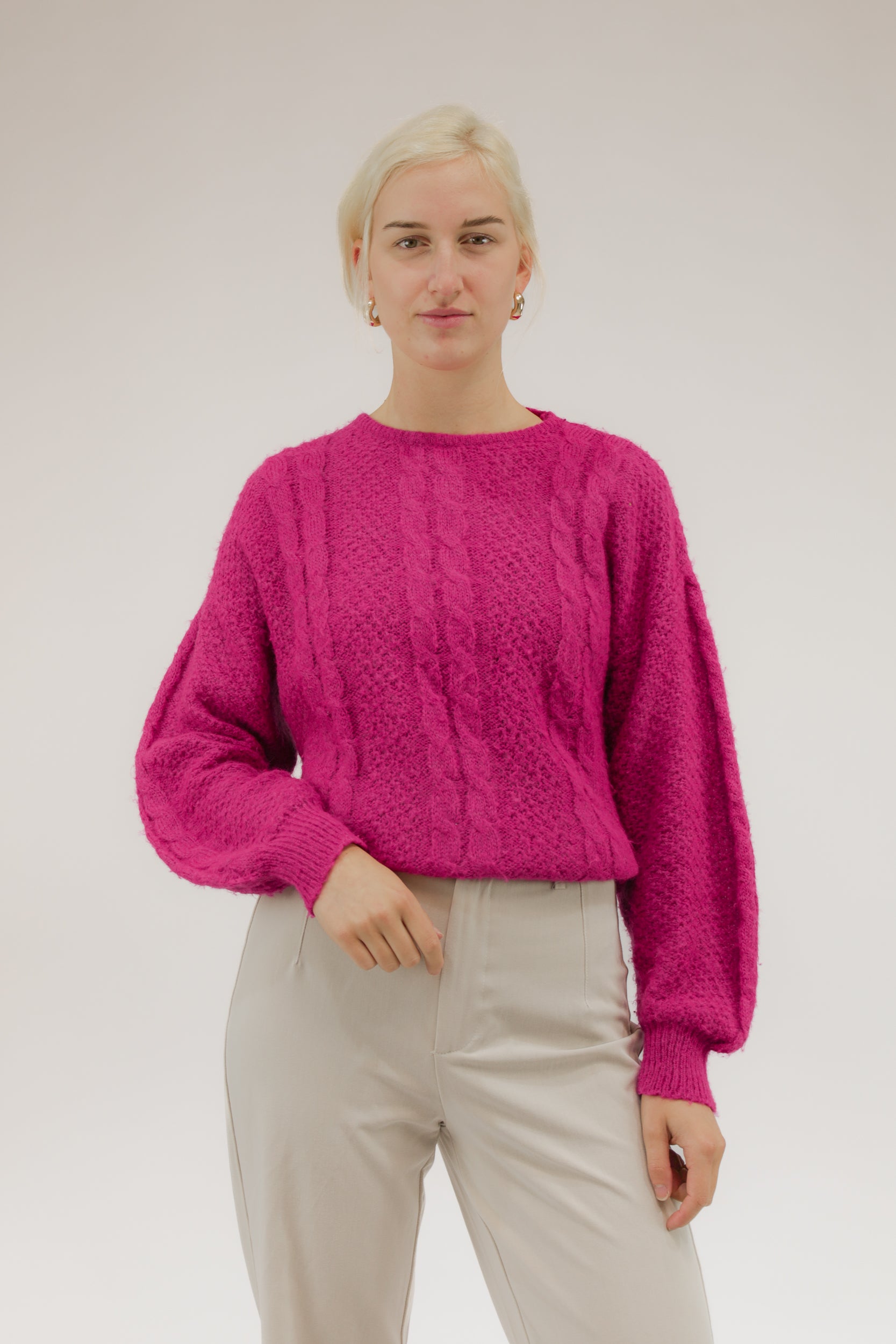 Model draagt zuurstokroze vintage trui met ingeweven kabelmotief – vooraanzicht.