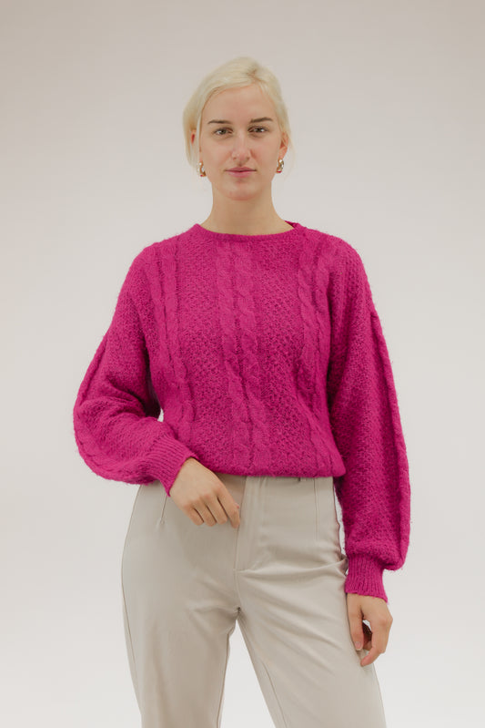 Model draagt zuurstokroze vintage trui met ingeweven kabelmotief – vooraanzicht.