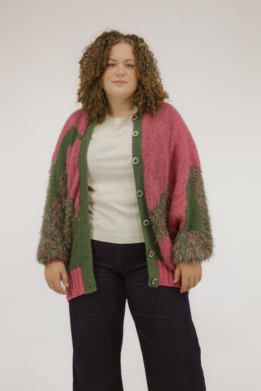 Model draagt oversized vintage vest in mosgroen met zuurstokroze accenten – vooraanzicht.