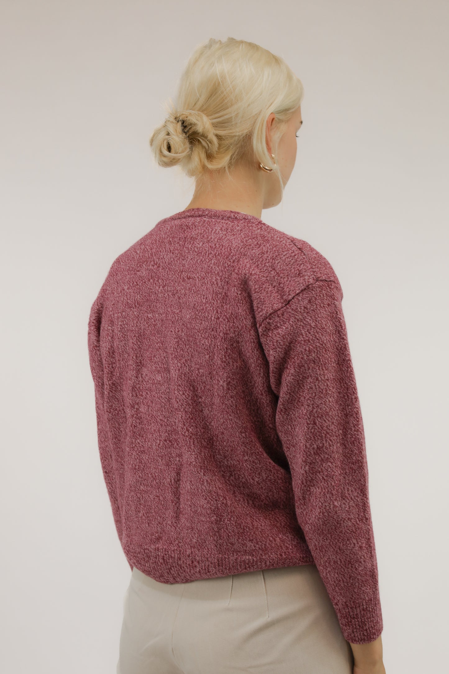 Achteraanzicht van model met vintage trui in roze wolmix, merk Grino.