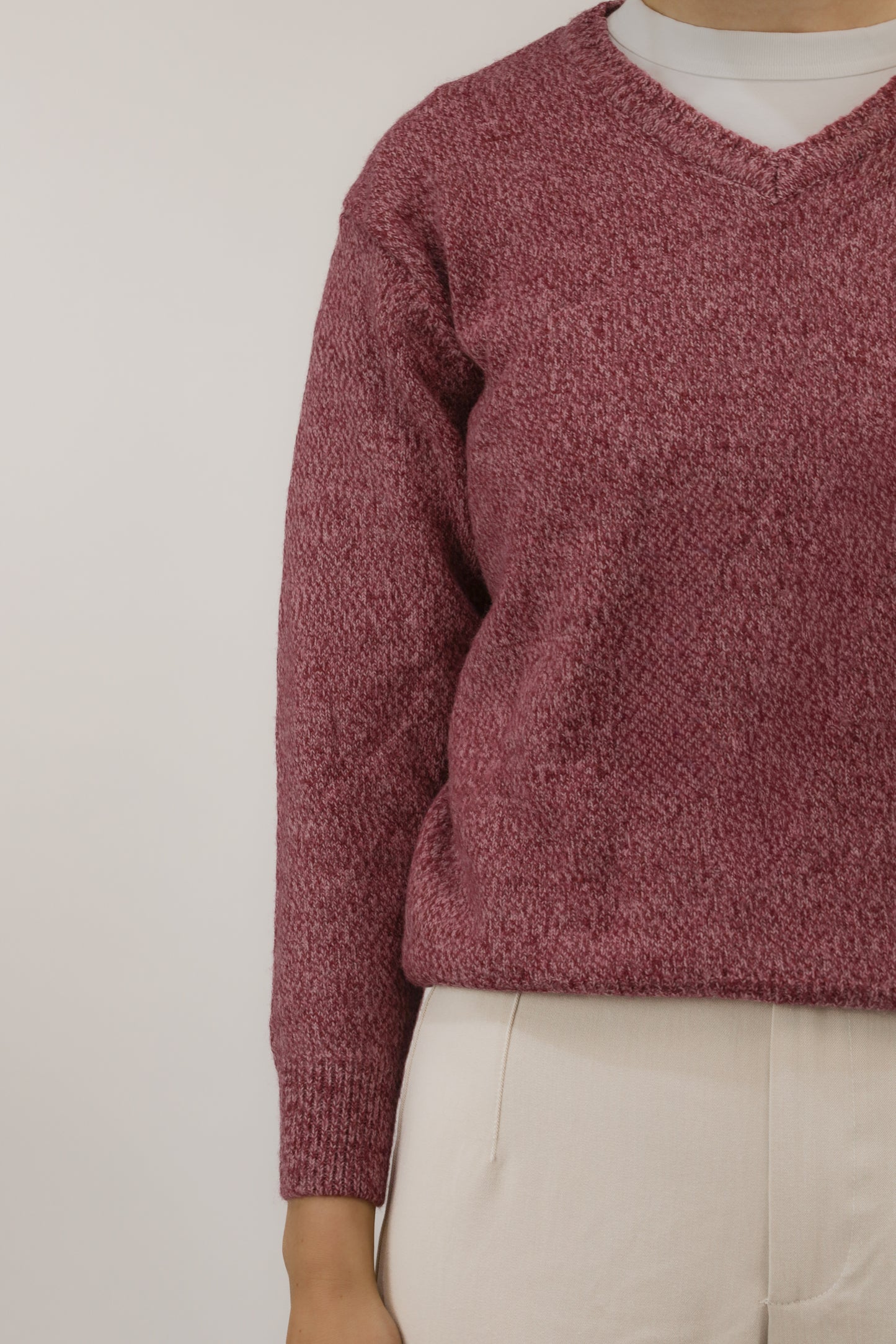 Detailopname van roze gemêleerd breisel en V-hals van de trui.