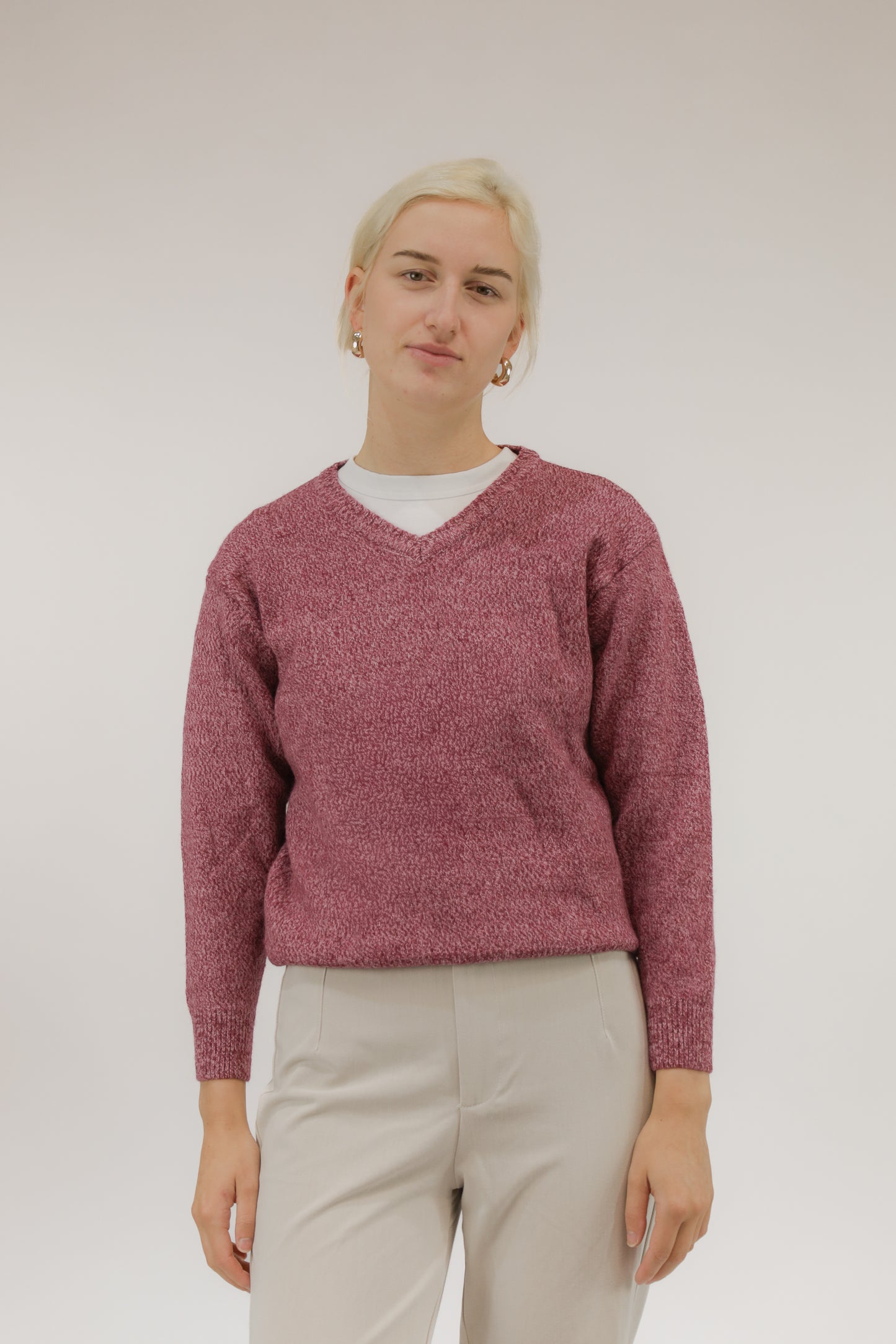 Vooraanzicht van model met roze melange vintage trui met V-hals.