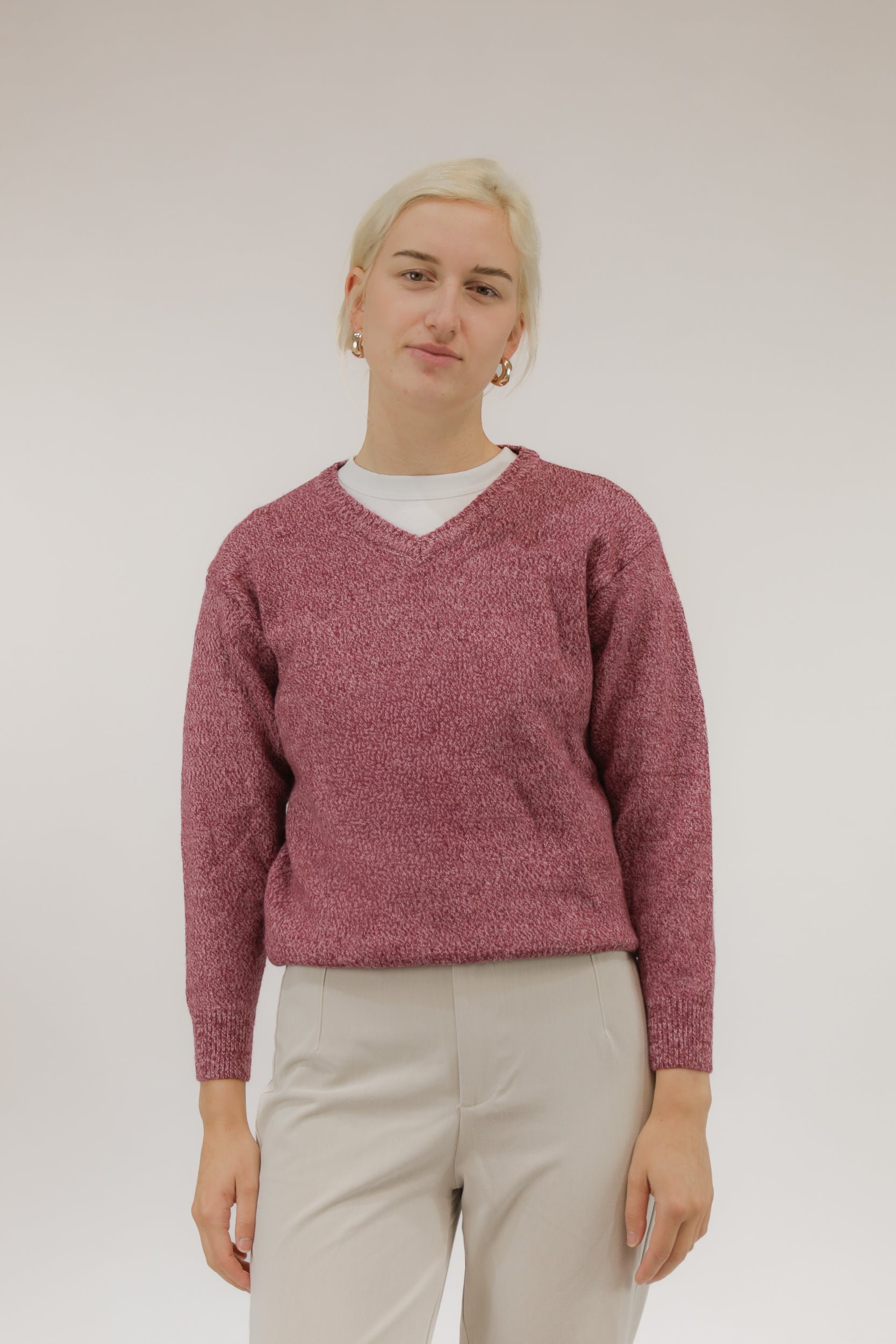 Vooraanzicht van model met roze melange vintage trui met V-hals.
