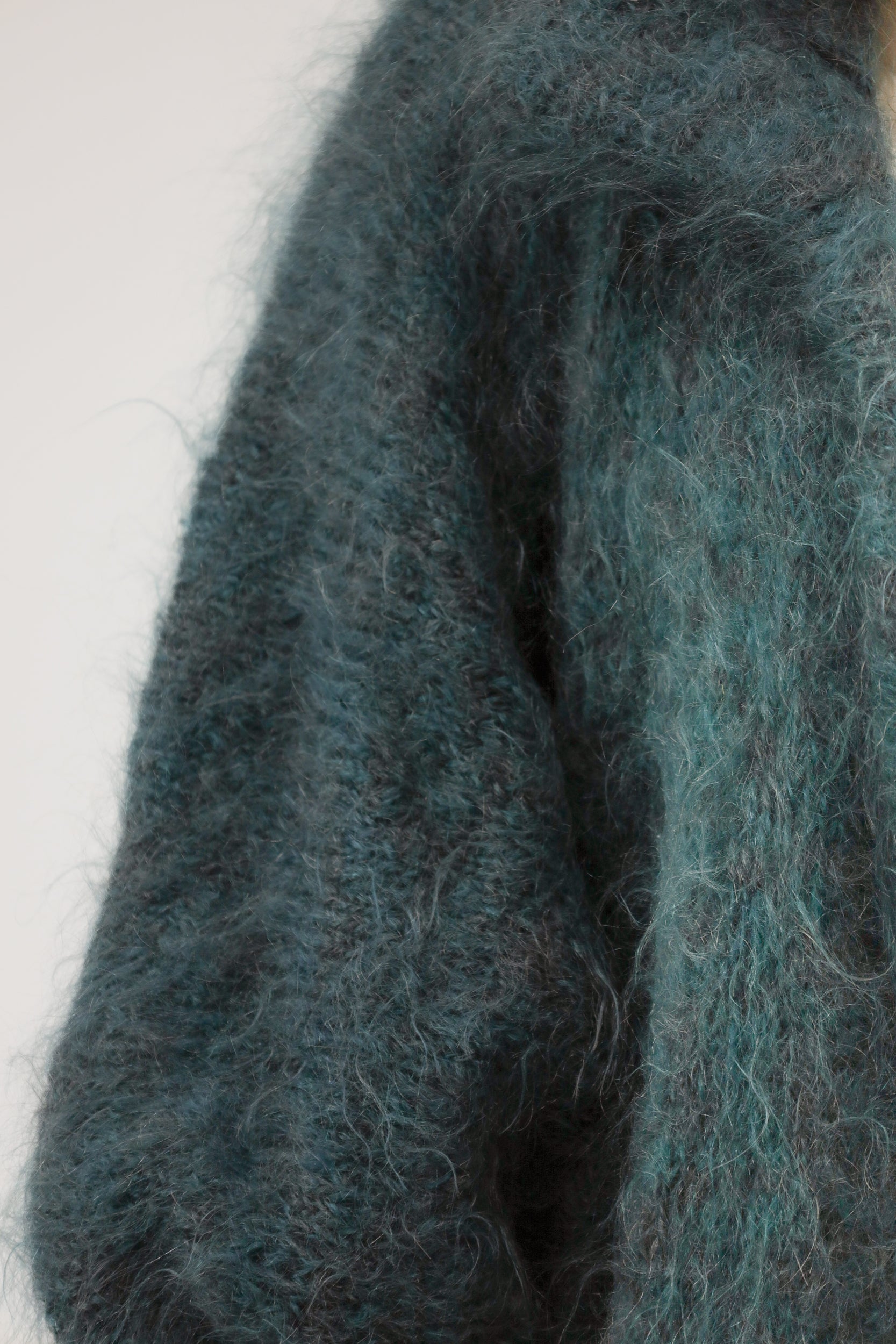 Close-up van model met vintage oversized knit – detail van zachte breistructuur in turkooisgroen.