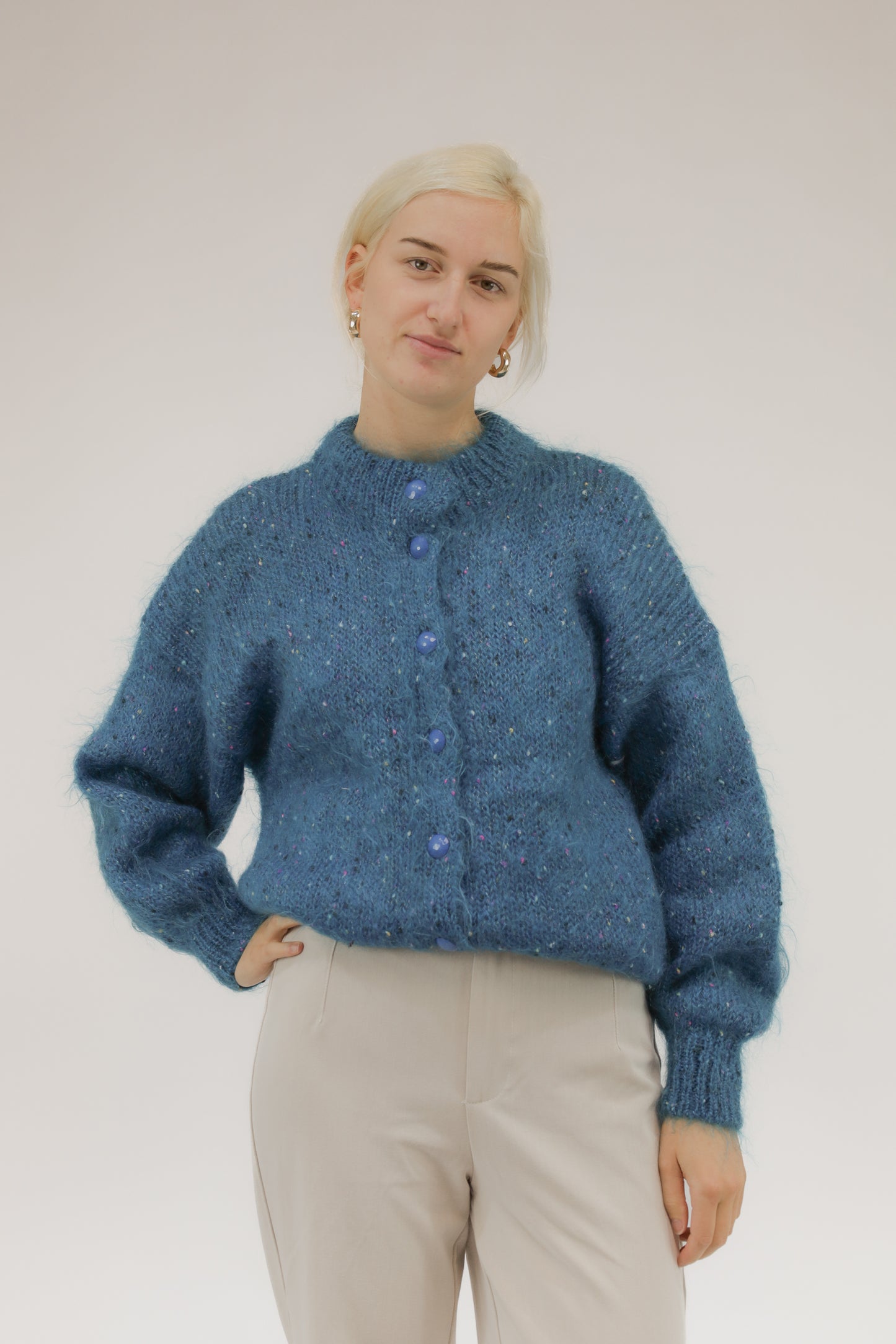 Model draagt vintage handgebreid turquoise vest met roze, paarse en off-white bolletjes – vooraanzicht.