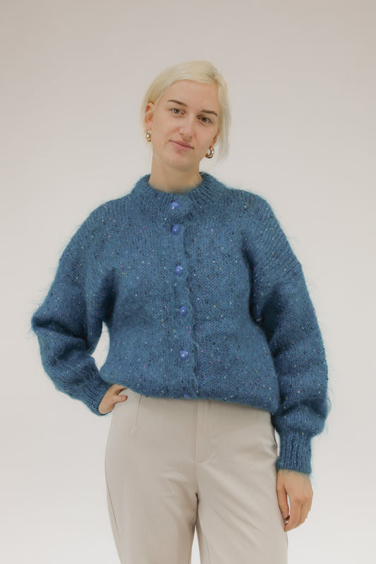 Model draagt vintage handgebreid turquoise vest met roze, paarse en off-white bolletjes – vooraanzicht.