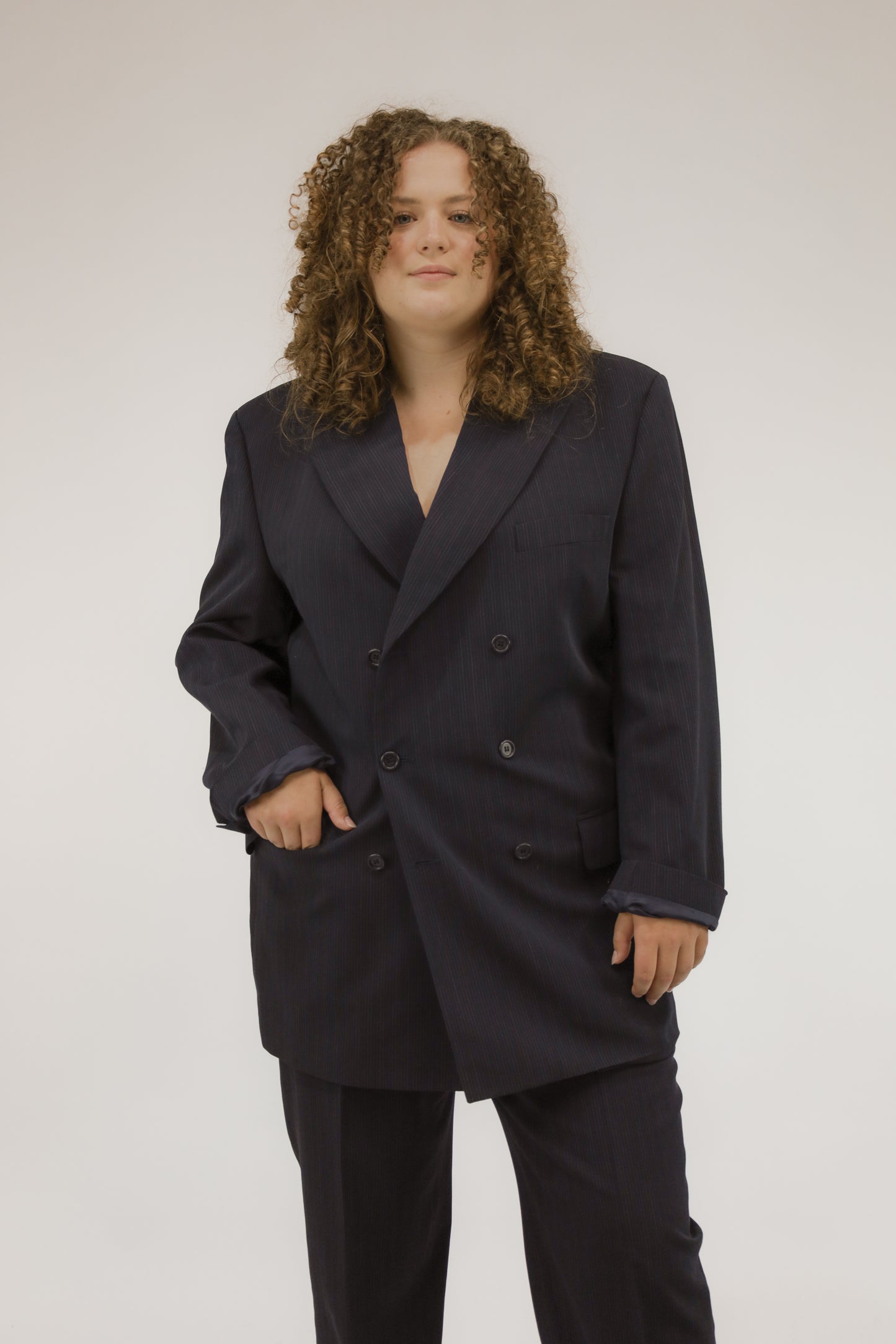 Vooraanzicht van model met donkerblauw vintage pak met krijtstreep, blazer en pantalon.