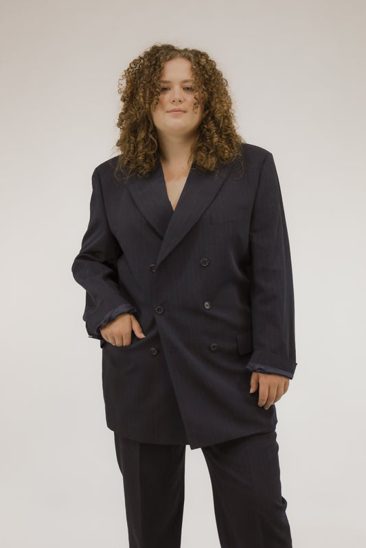 Vooraanzicht van model met donkerblauw vintage pak met krijtstreep, blazer en pantalon.