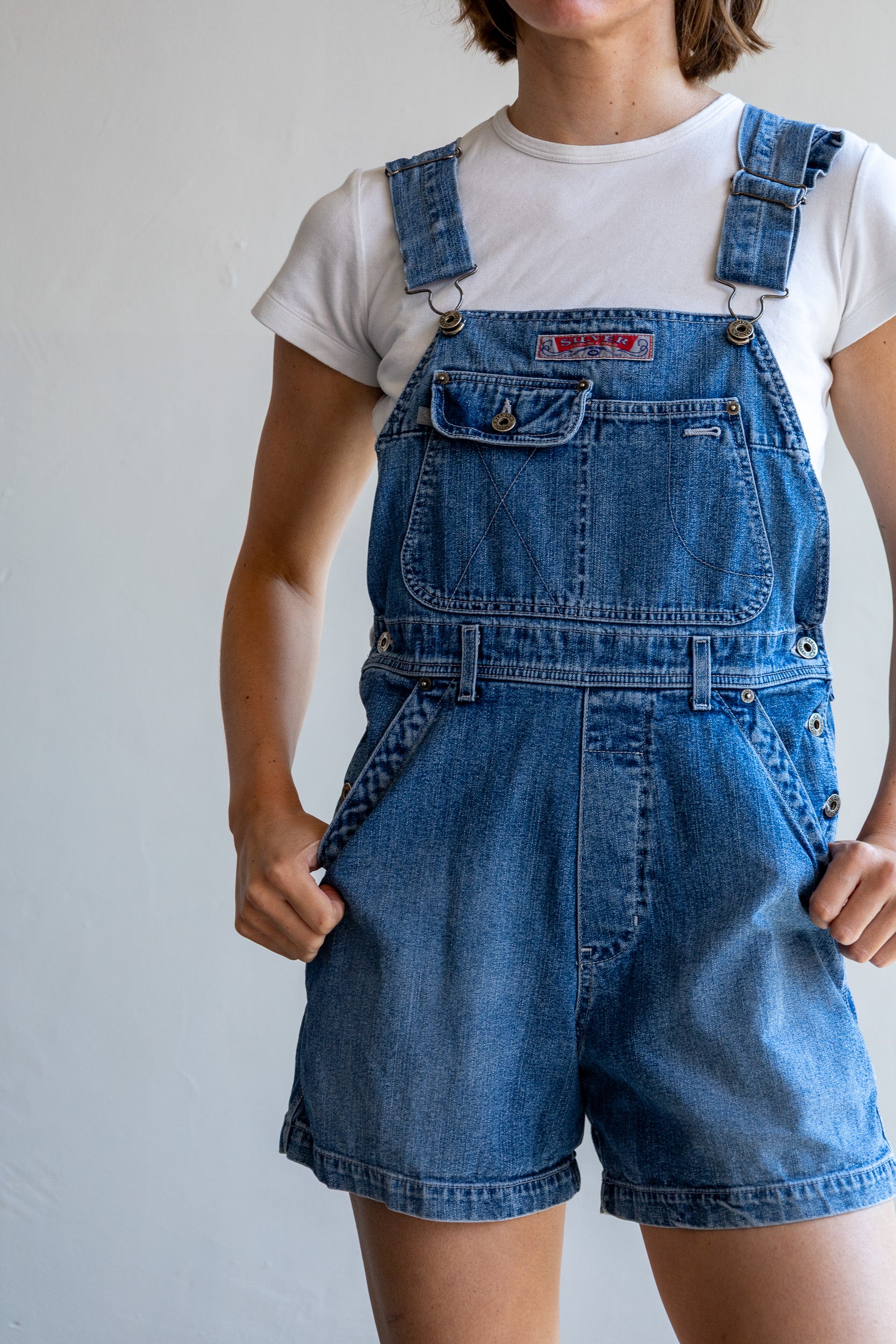 Detail van de vintage denim jumpsuit met klassieke tuinbroekdetails en denim stof.