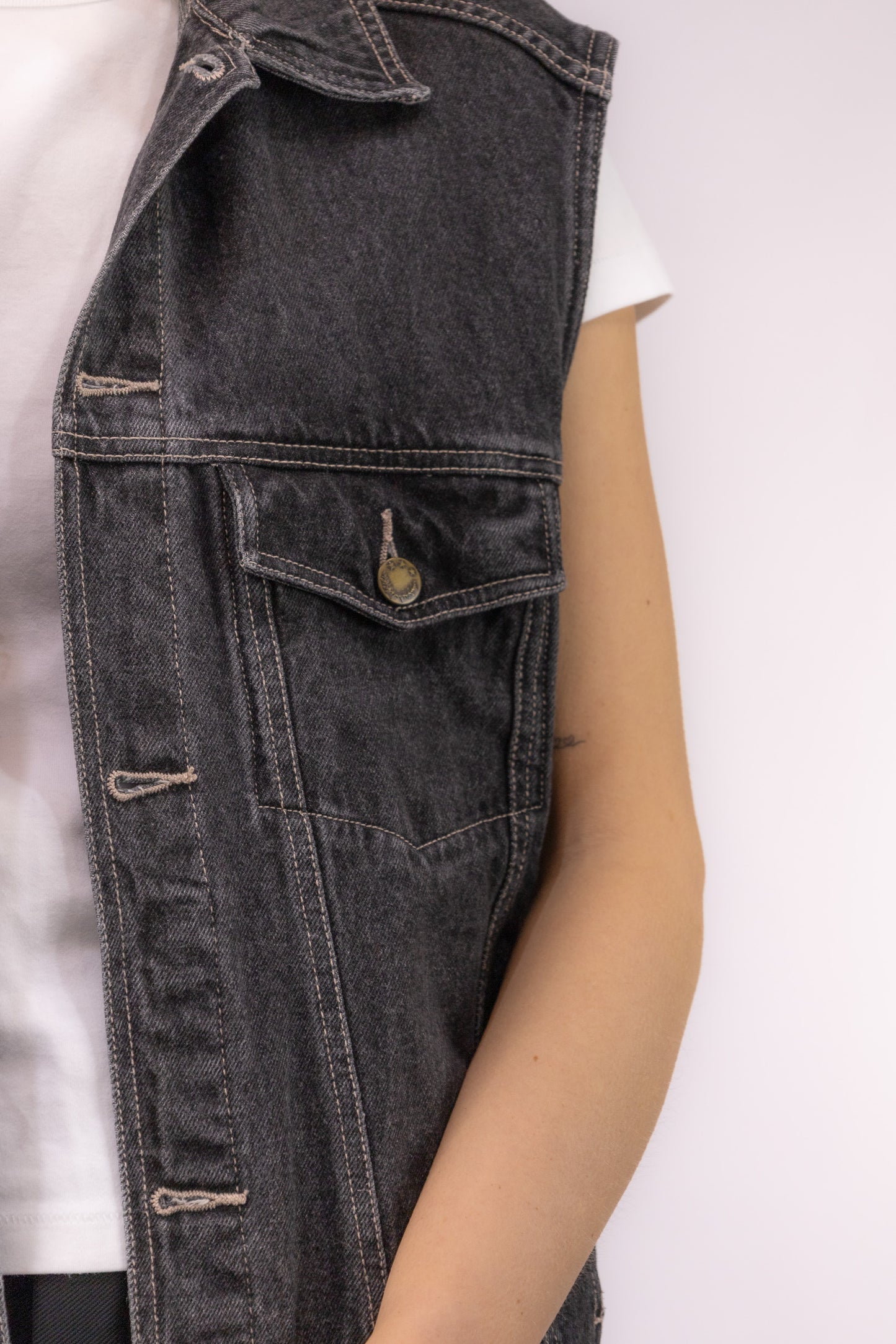 Detail van gewassen zwart denim met klassieke stiksels en knoopsluiting op vintage gilet