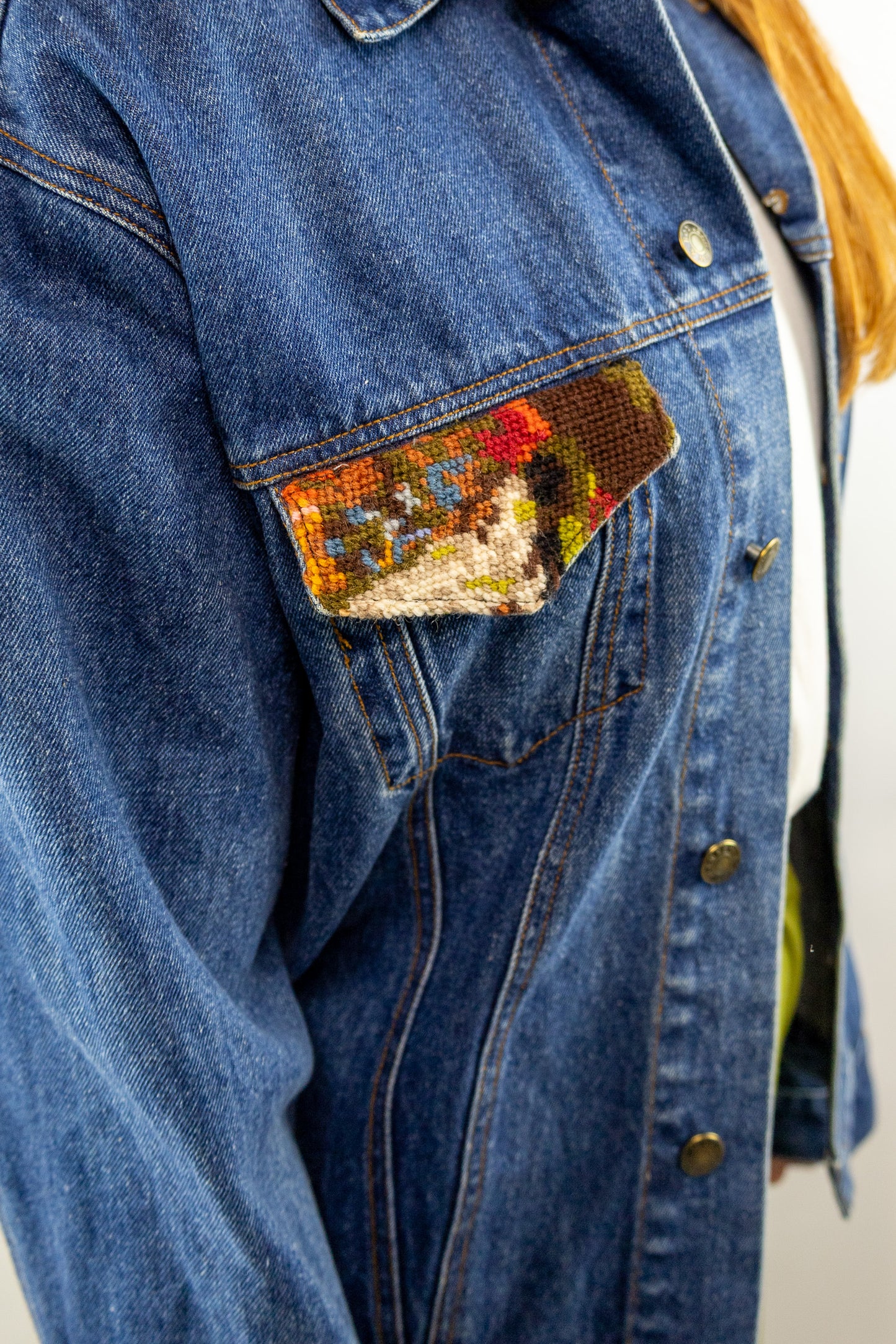 detail van kleurrijk borduurwerk op vintage denim jas