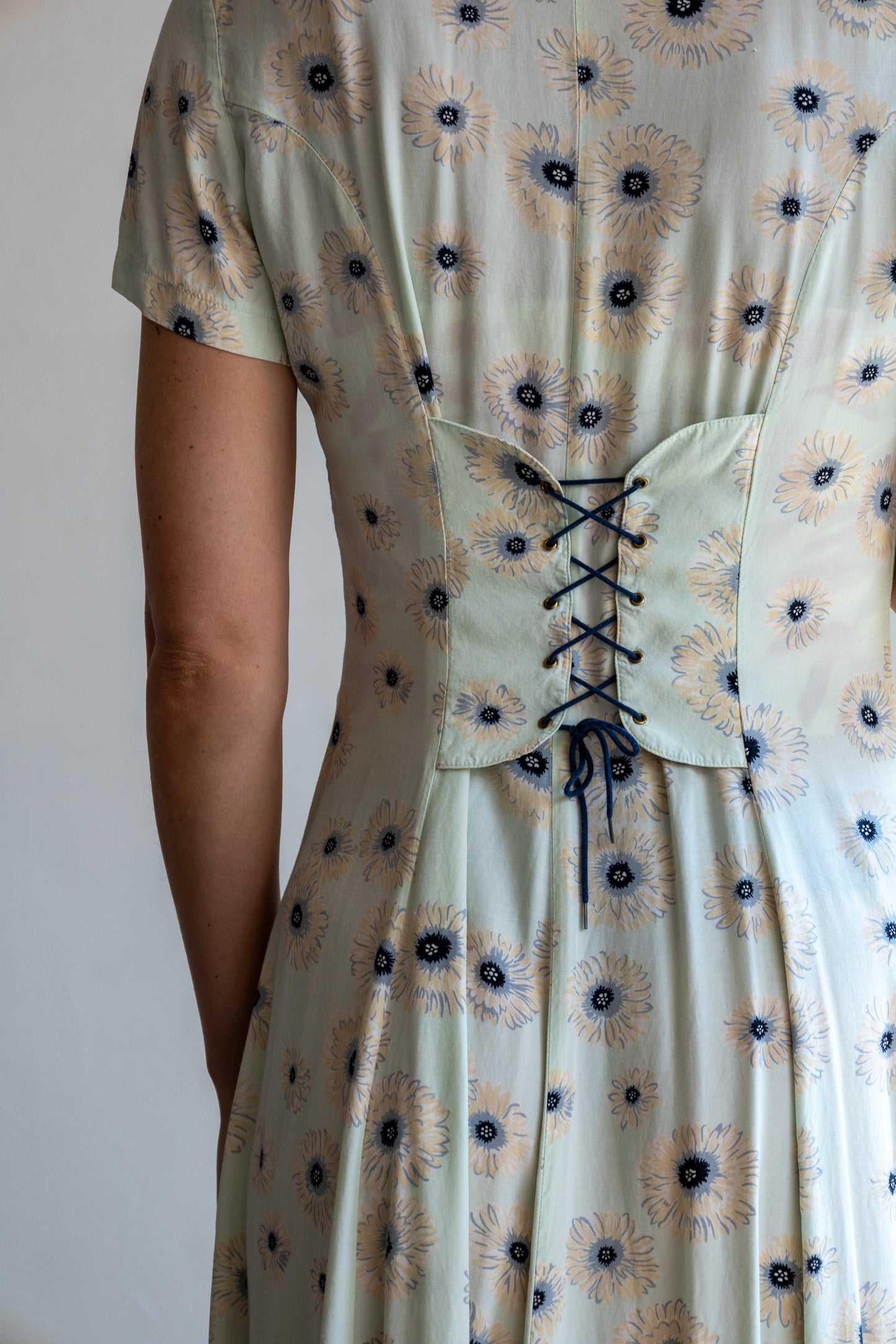 Detail van de vintage bloemenjurk met mintgroene stof en verfijnde bloemenprint.