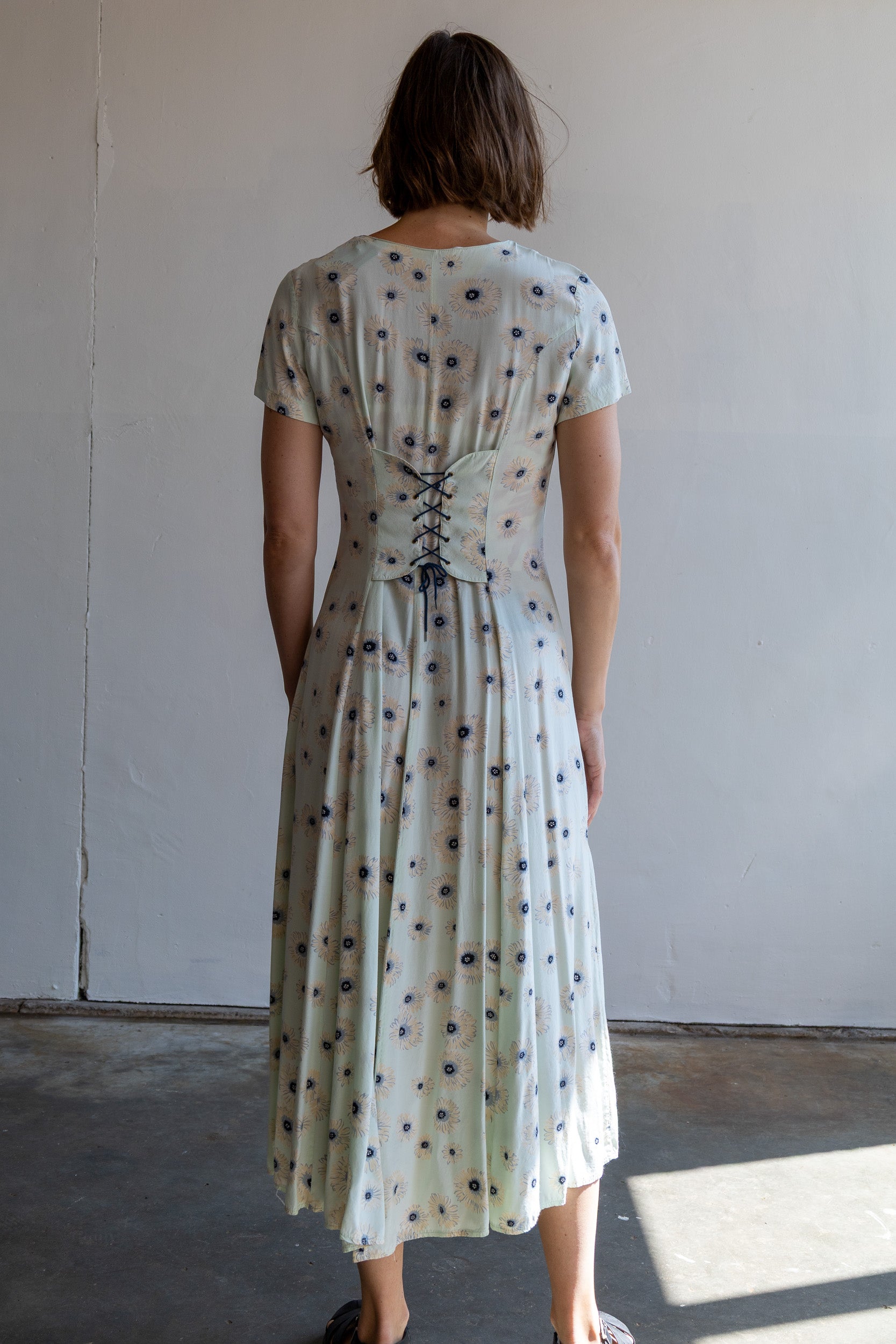 Achterzijde van de vintage jurk met corsetachtige strikceintuur op het achterpand.