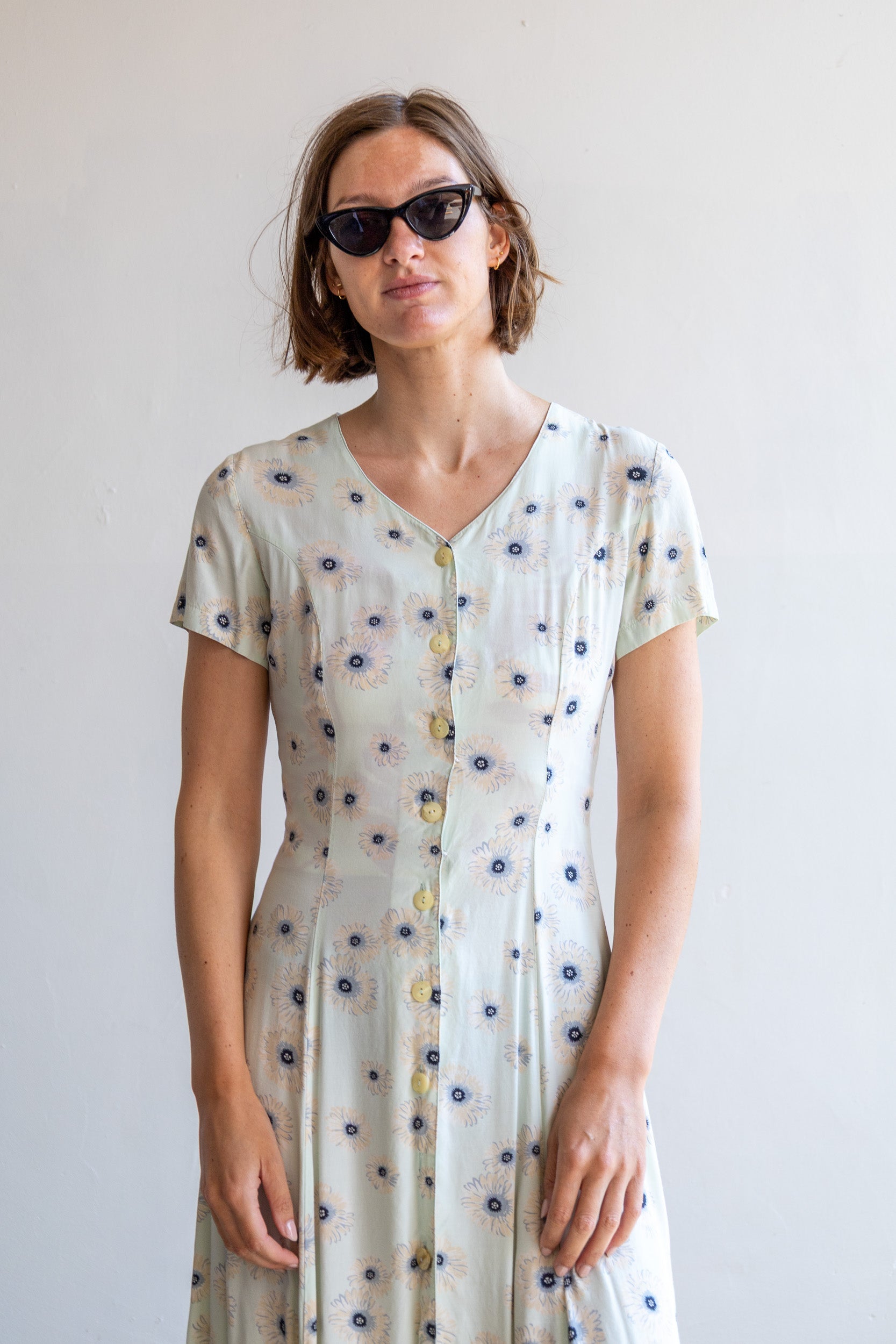 Vintage mintgroene jurk met donkerblauw-beige bloemenprint en vrouwelijk silhouet.