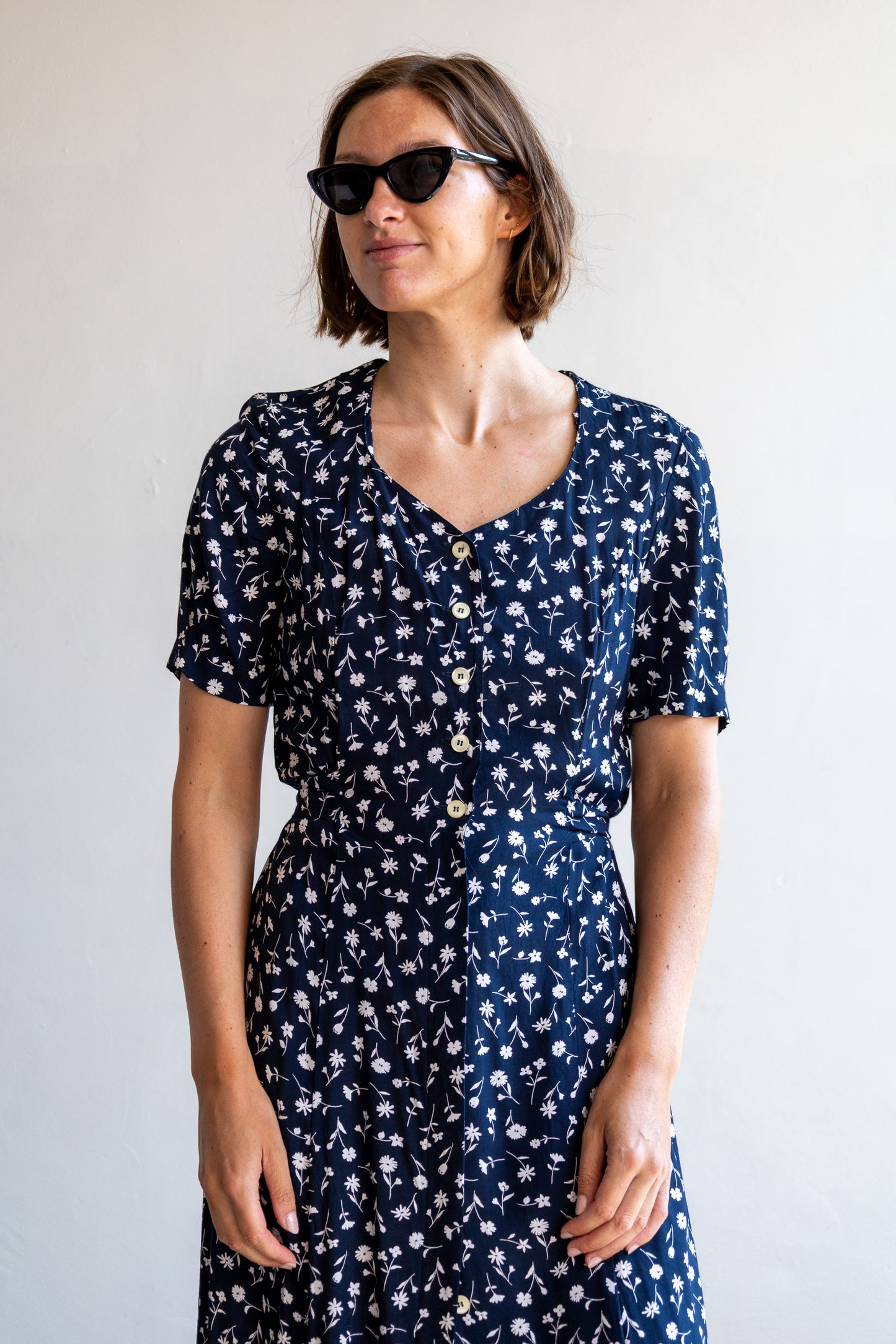 Vintage donkerblauwe viscose jurk met wit bloemenmotief en knoopsluiting.
