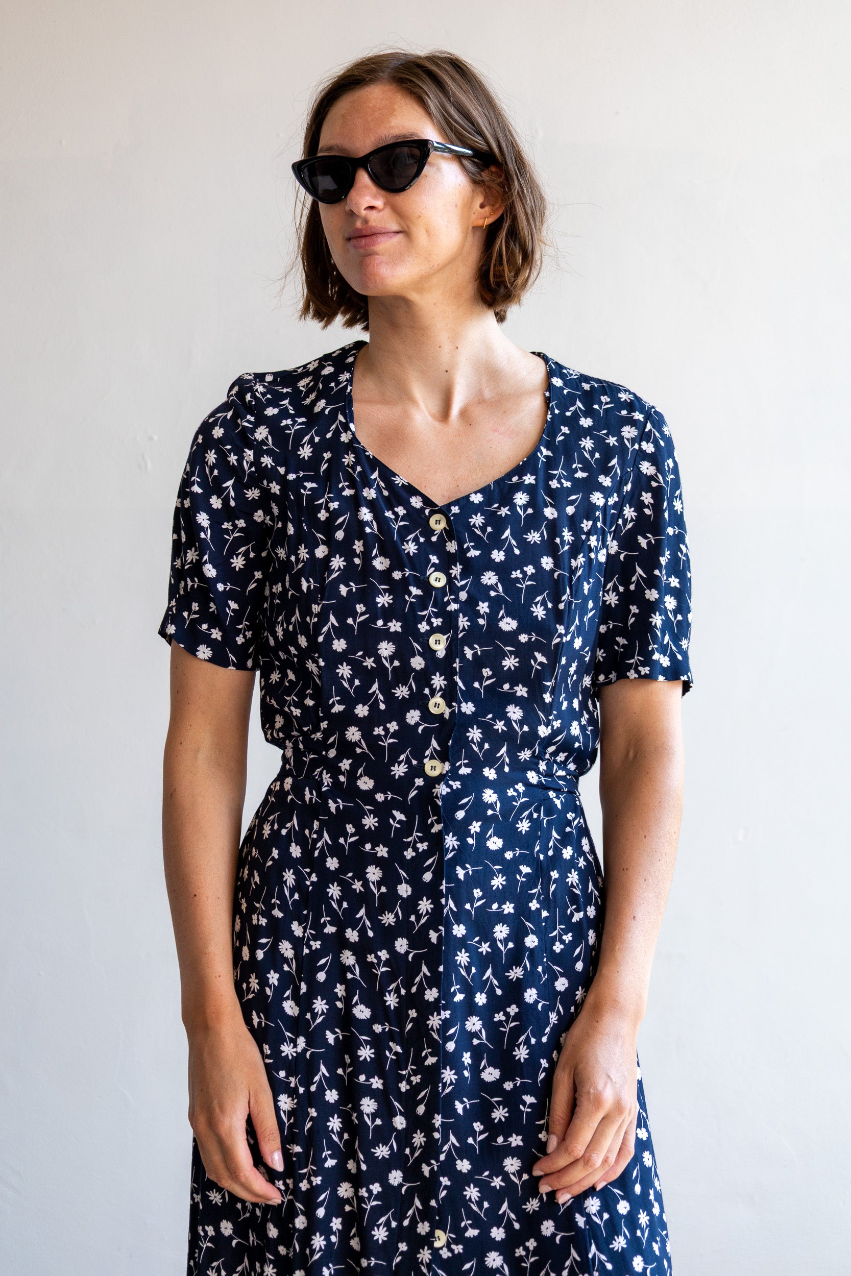 Vintage donkerblauwe viscose jurk met wit bloemenmotief en knoopsluiting.