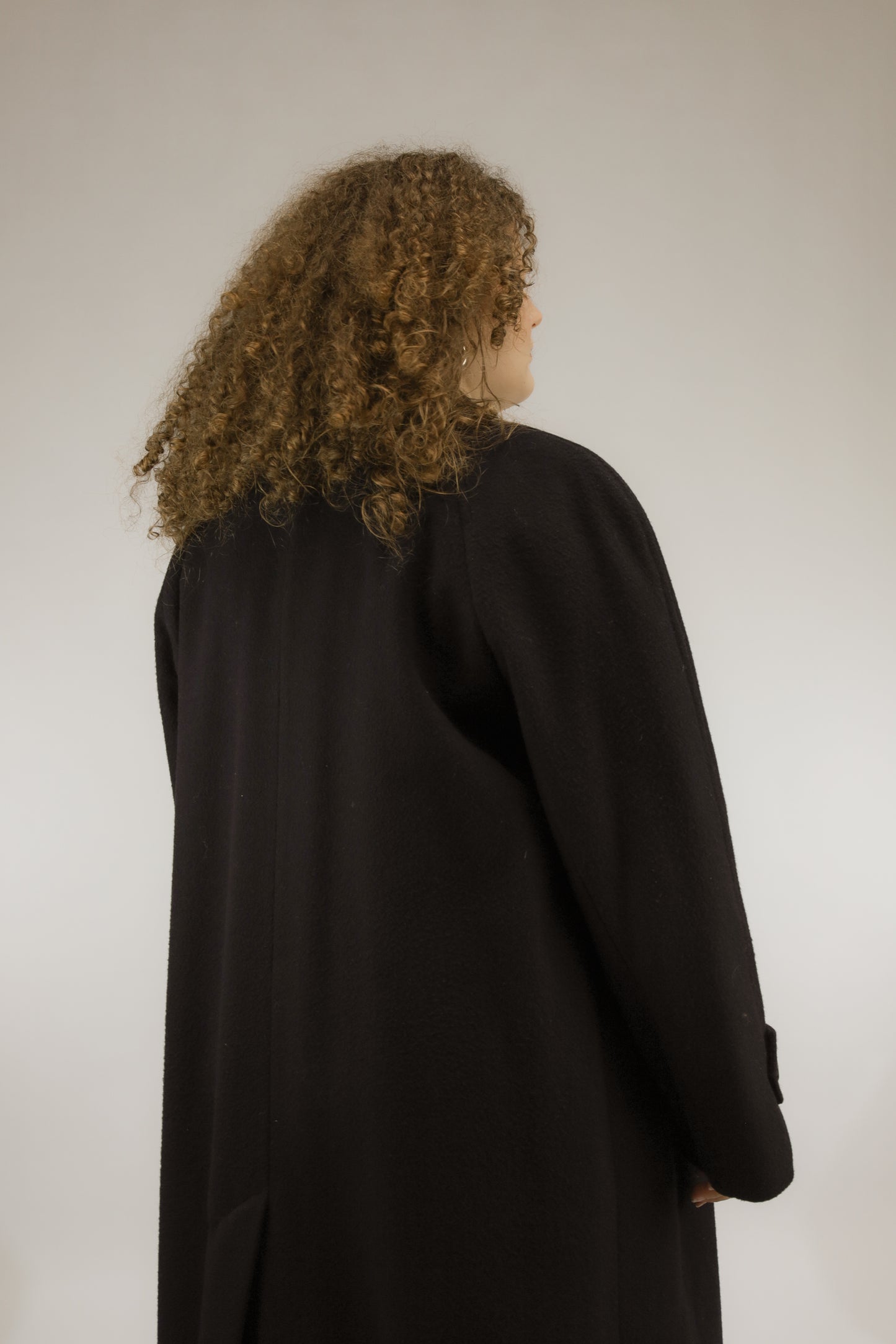 Achteraanzicht van lange zwarte oversized vintage mantel met raglan mouwen