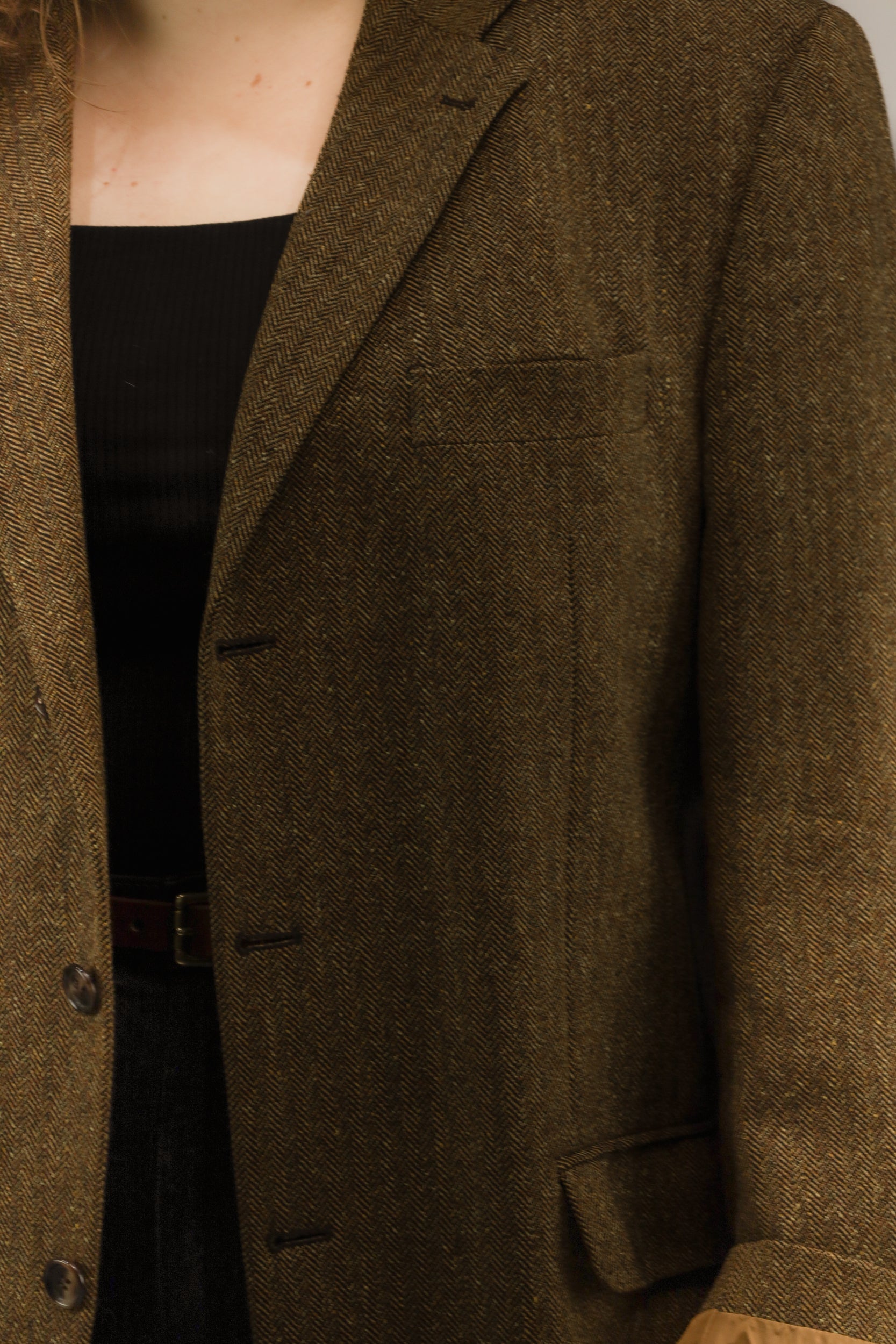 Detail van het bruine visgraatmotief en klassieke afwerking van vintage blazer