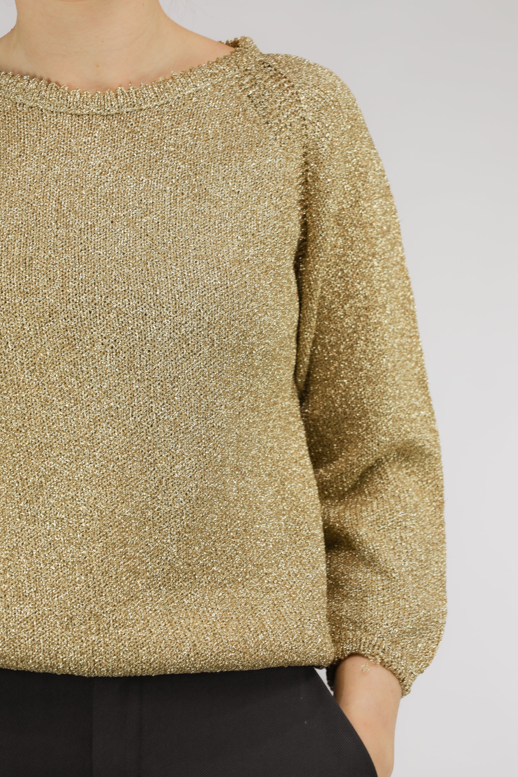Detail van goudkleurige knit en subtiele pofmouw van vintage trui