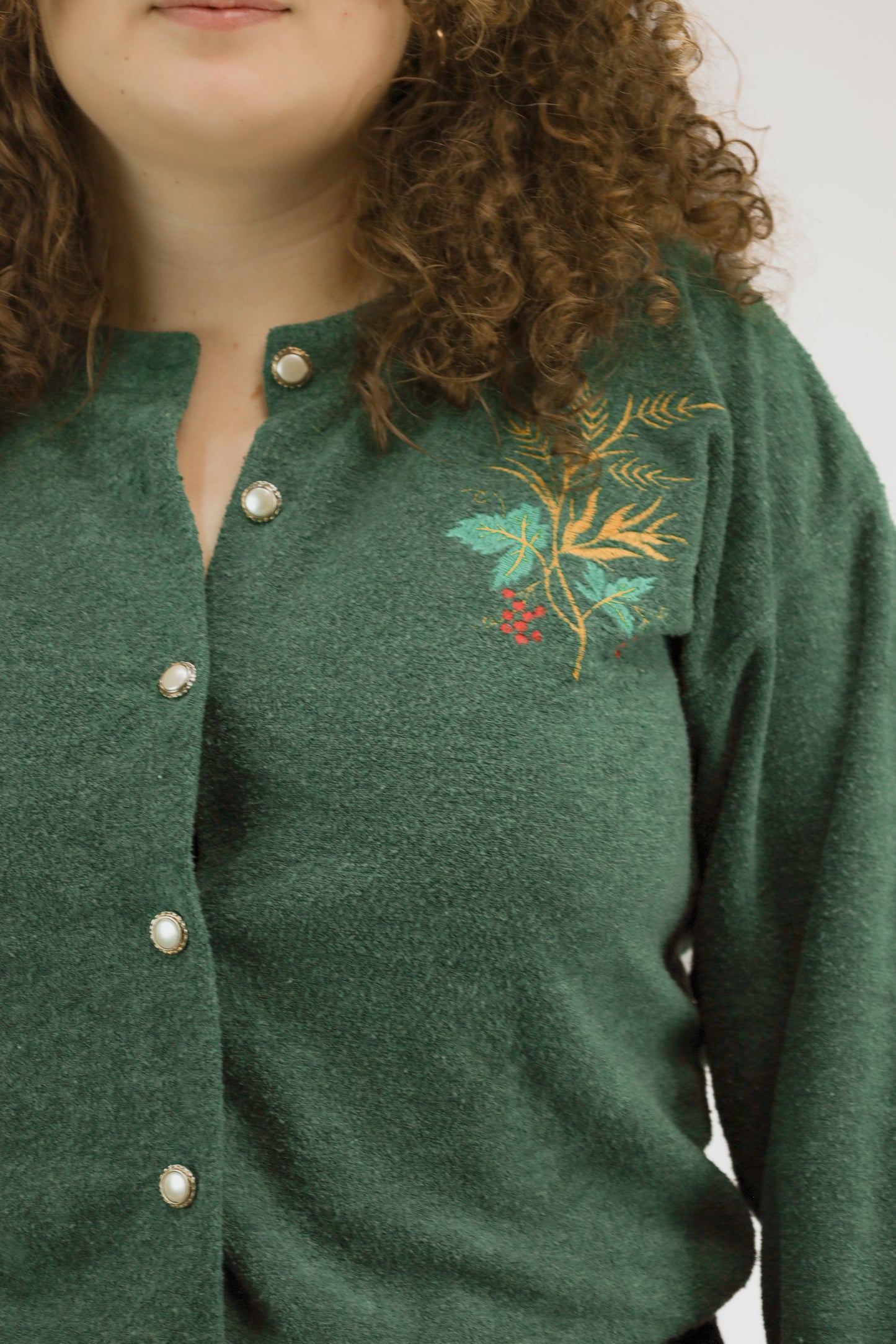 Detail van kerstborduursel en parelknopen op groen gebreid vintage vest