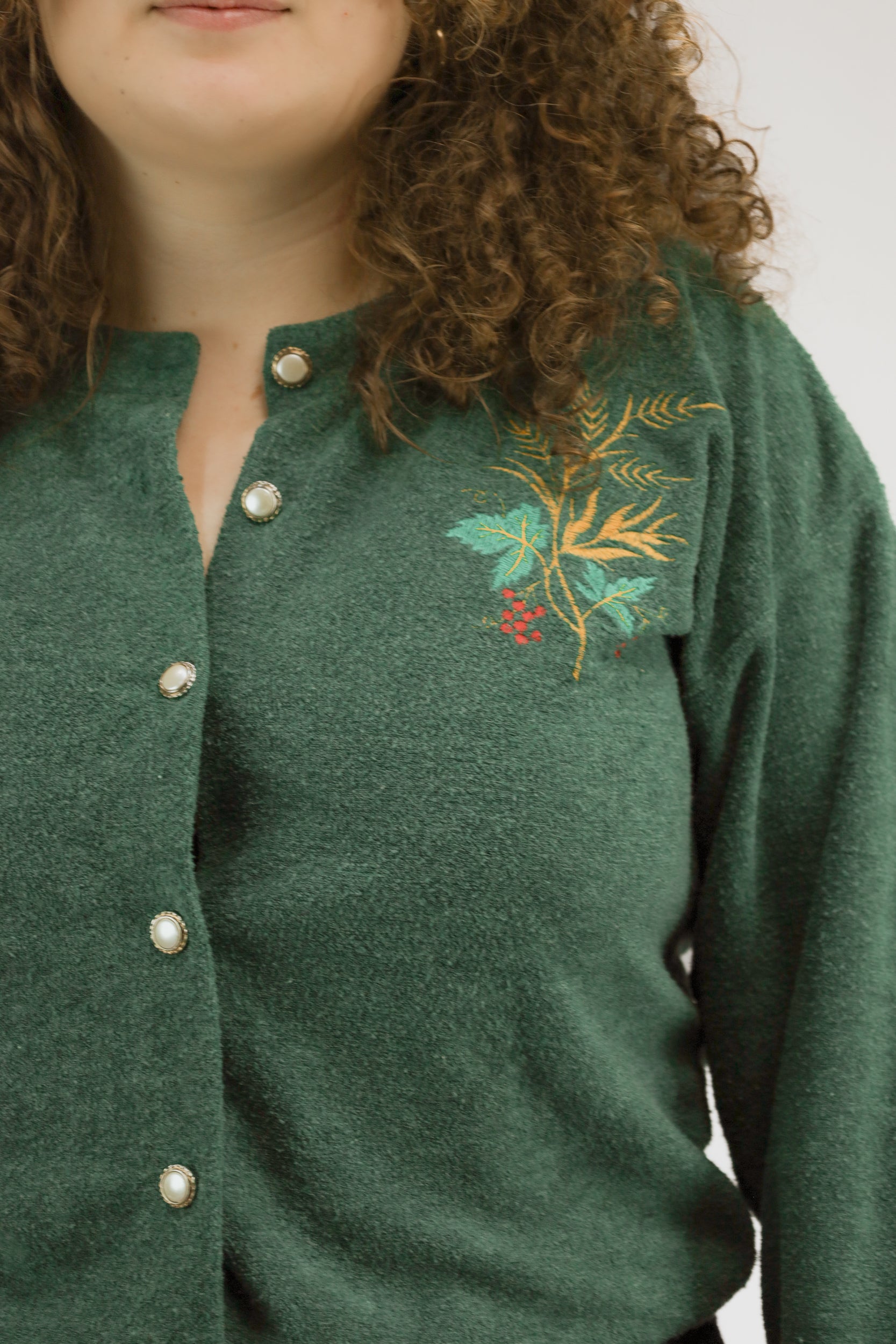 Detail van kerstborduursel en parelknopen op groen gebreid vintage vest