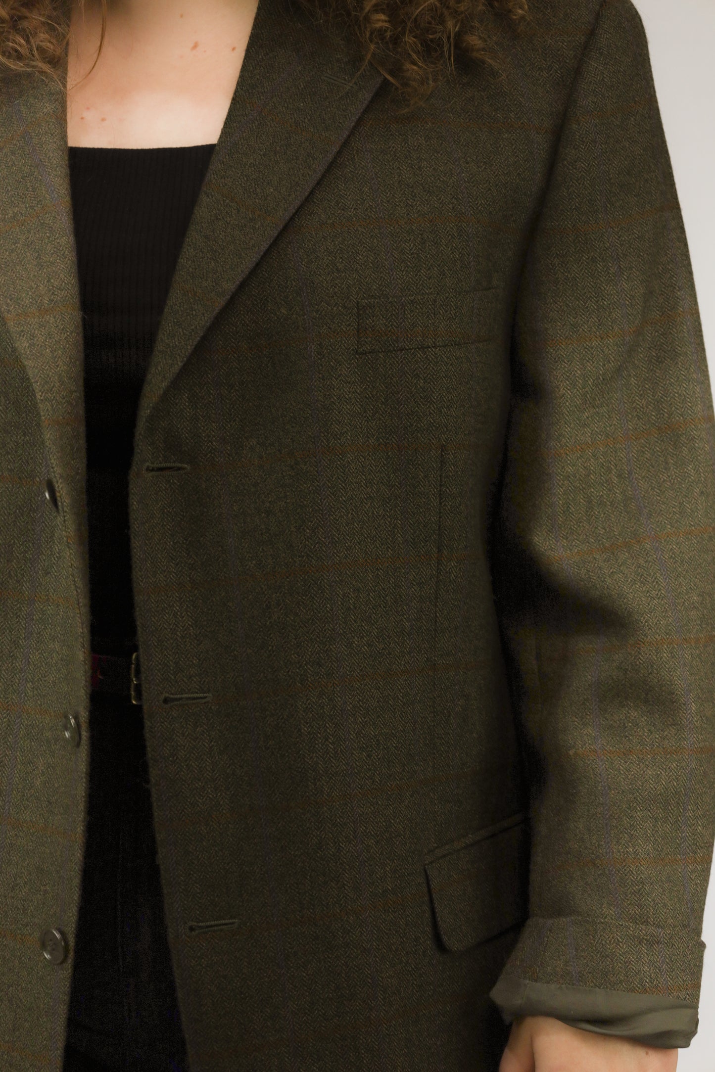 Detail van bruine visgraatstof en fijn blokpatroon van vintage wollen blazer