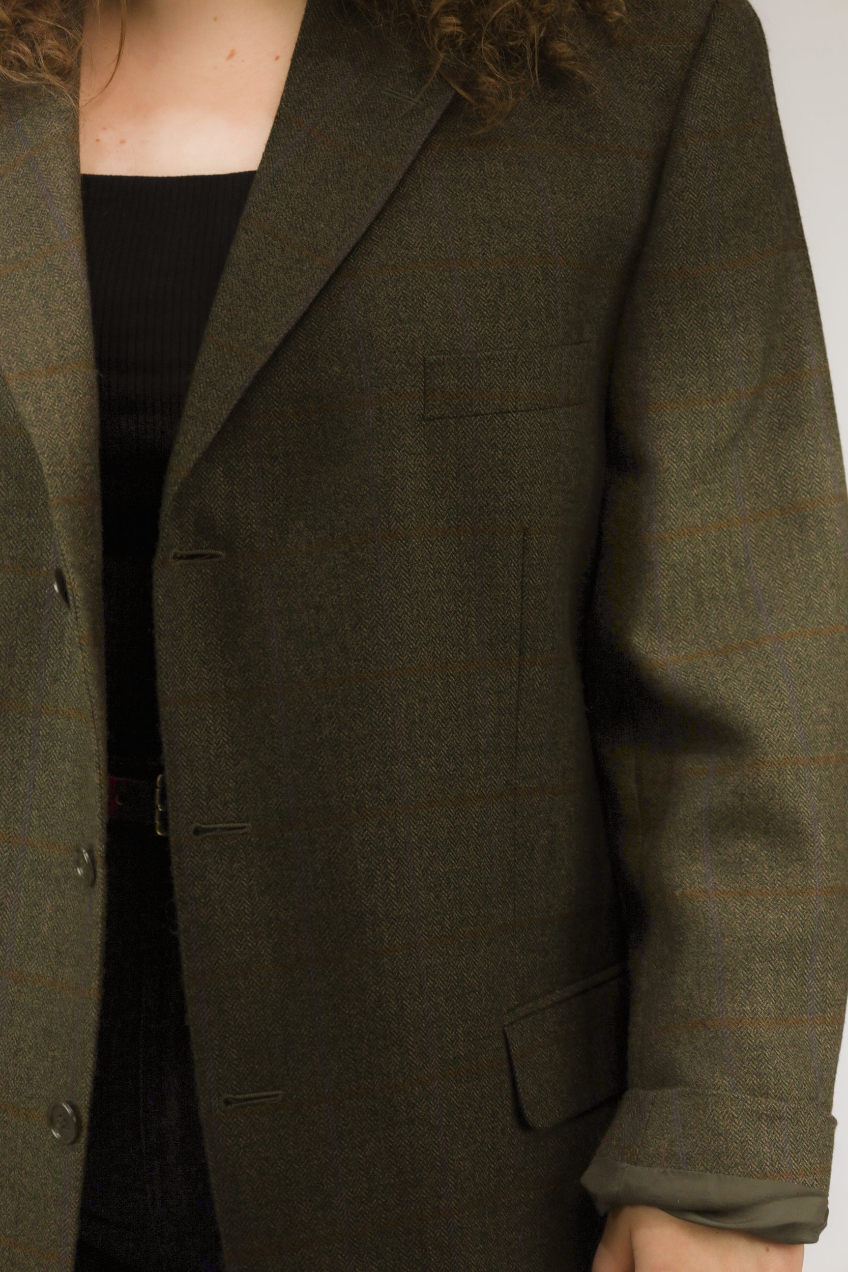 Detail van bruine visgraatstof en fijn blokpatroon van vintage wollen blazer