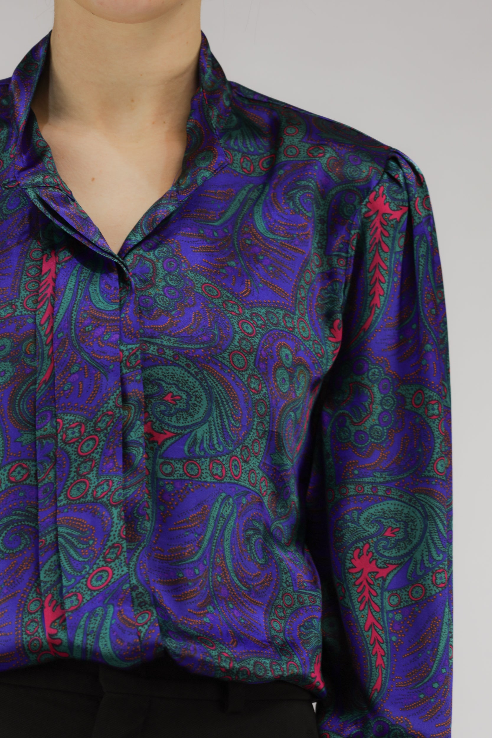 Detail van paisleyprint en plooien in de mouw van paarse vintage blouse