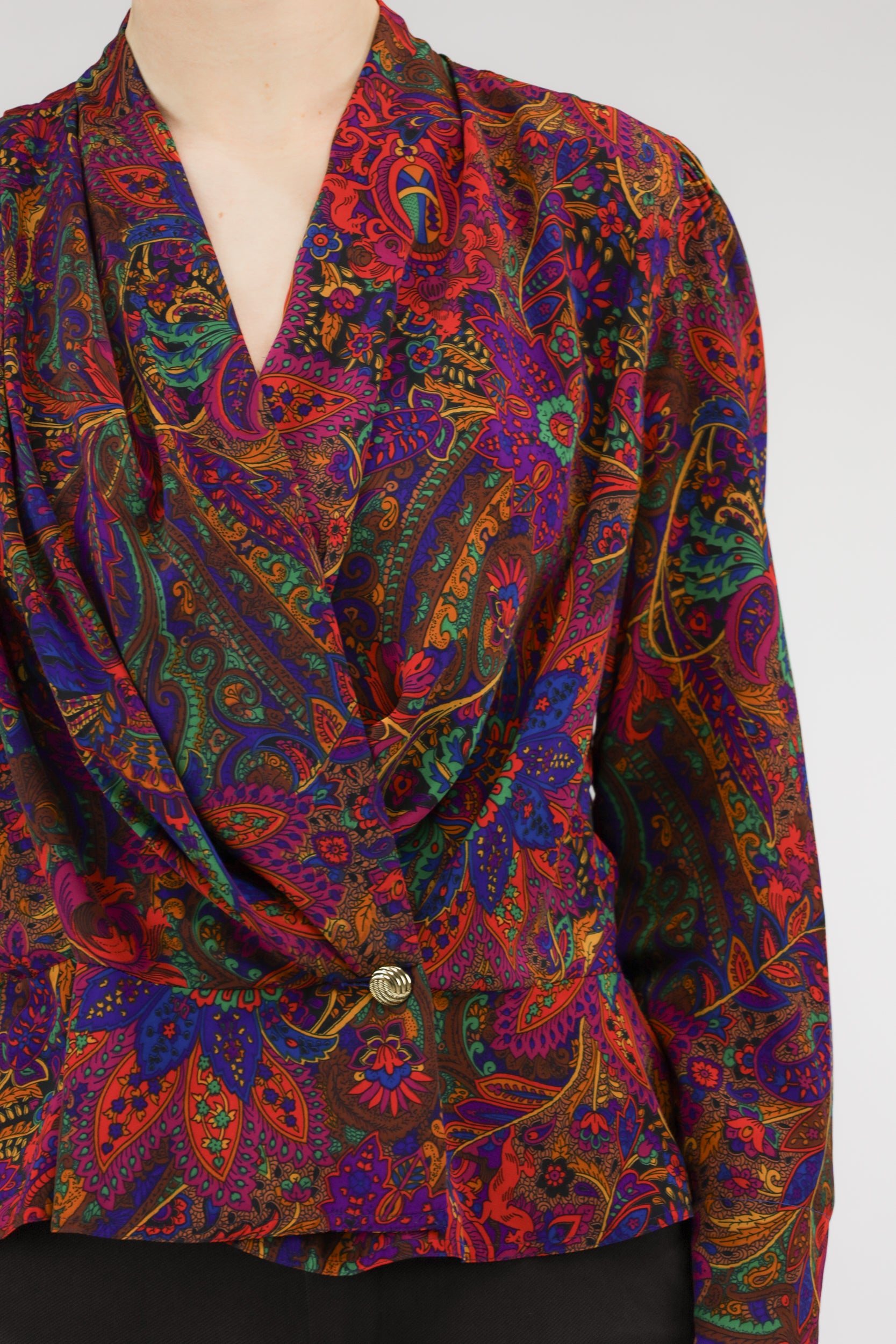 Detail van paisleyprint, gouden knoop en geplooid sjaalkraagje van vintage blouse