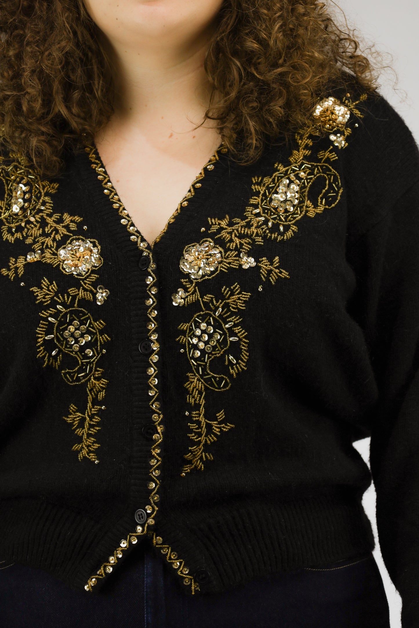 Detail van goudgeborduurde glitters en knoopbeleg van zwart vintage vest